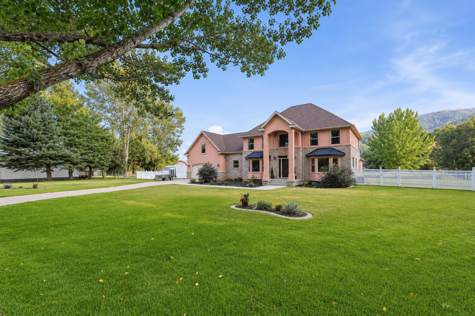 Stately two-story residence featuring a salmon-colored exterior with stone accents and a dark-shingled roof