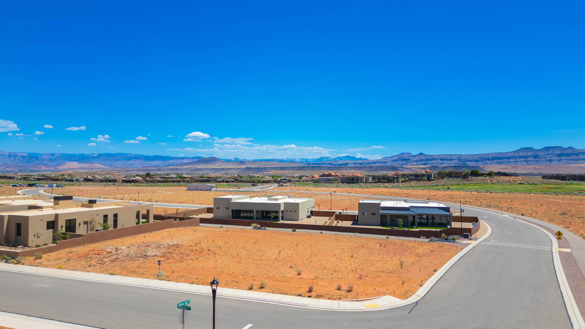 Expansive undeveloped lot featuring street frontage, curvilinear road design, and distant mountain scenery