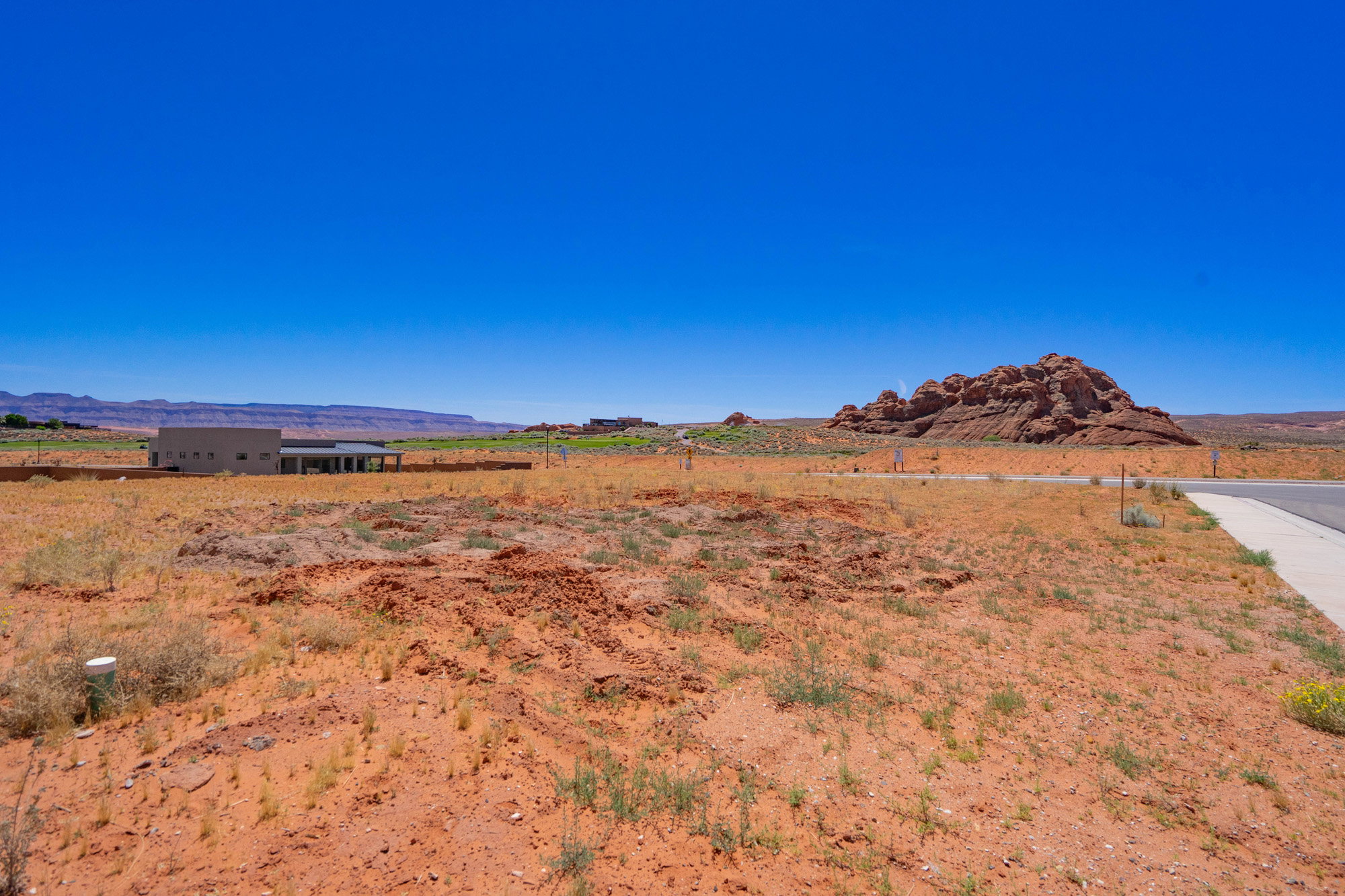 Expansive undeveloped land featuring a paved road frontage, utility access points, and natural rock formations