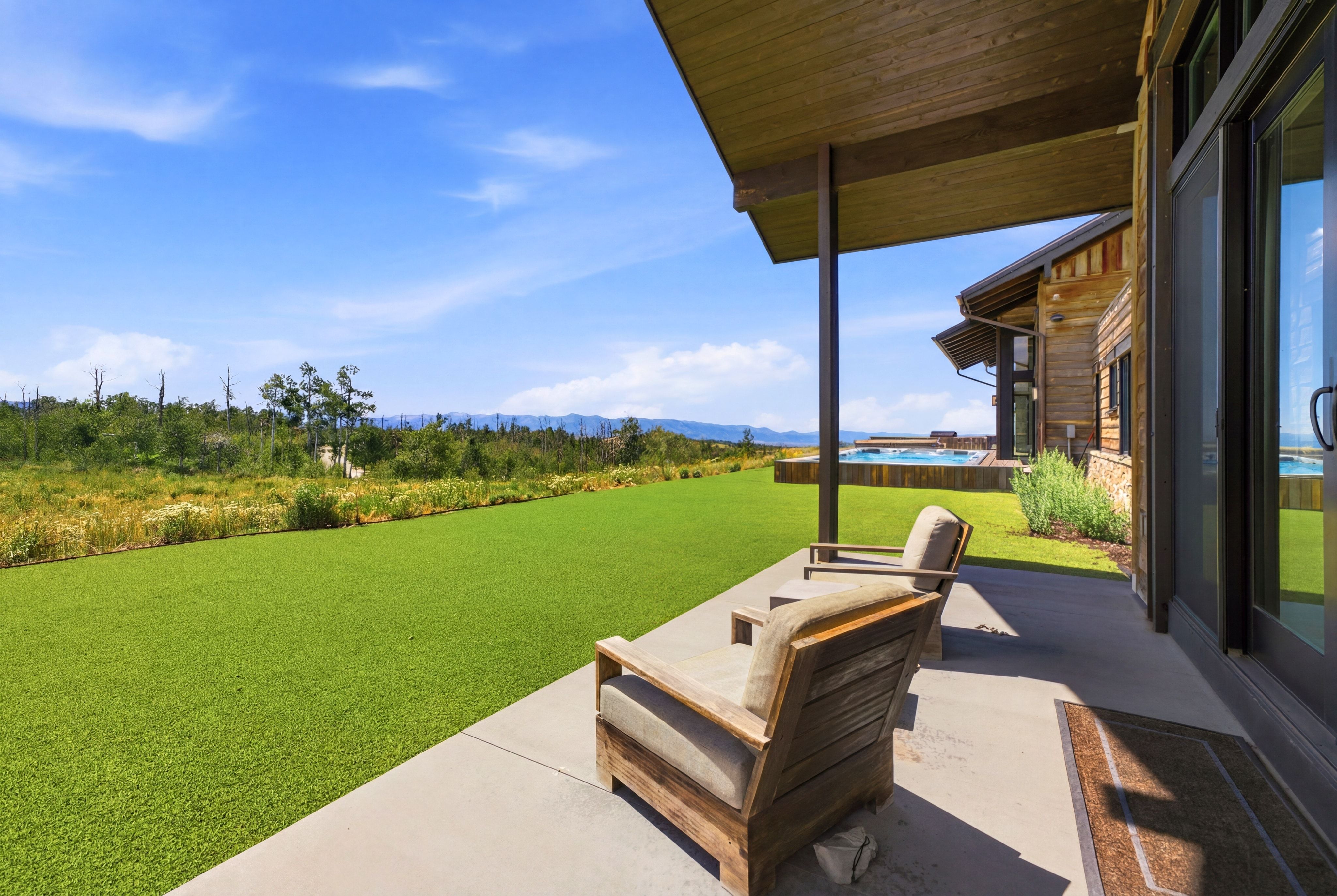 Covered patio featuring concrete flooring, a timber ceiling, and two wood-frame outdoor chairs