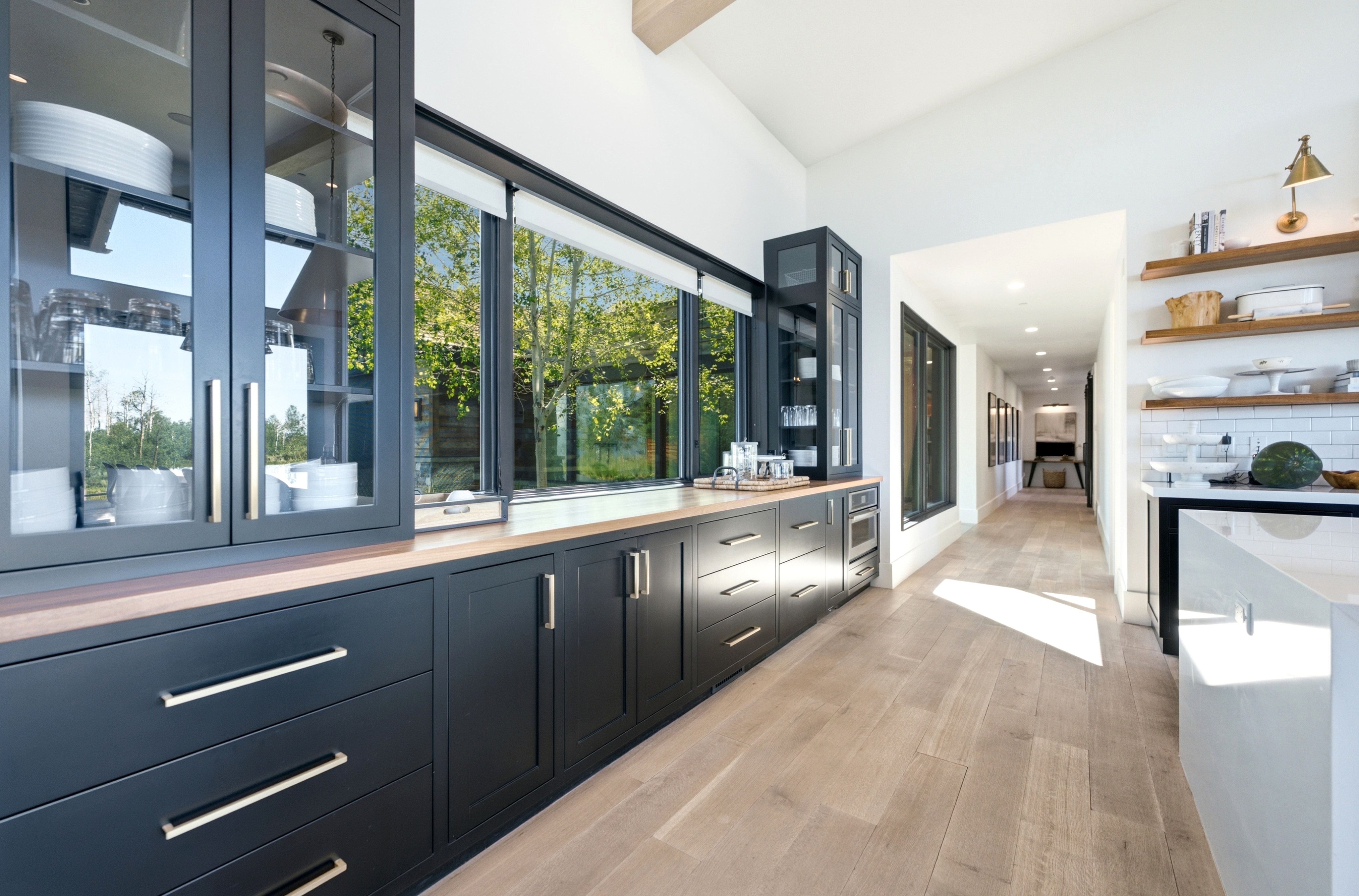 Kitchen featuring extensive black cabinetry, wood-finish countertops, and a full wall of windows