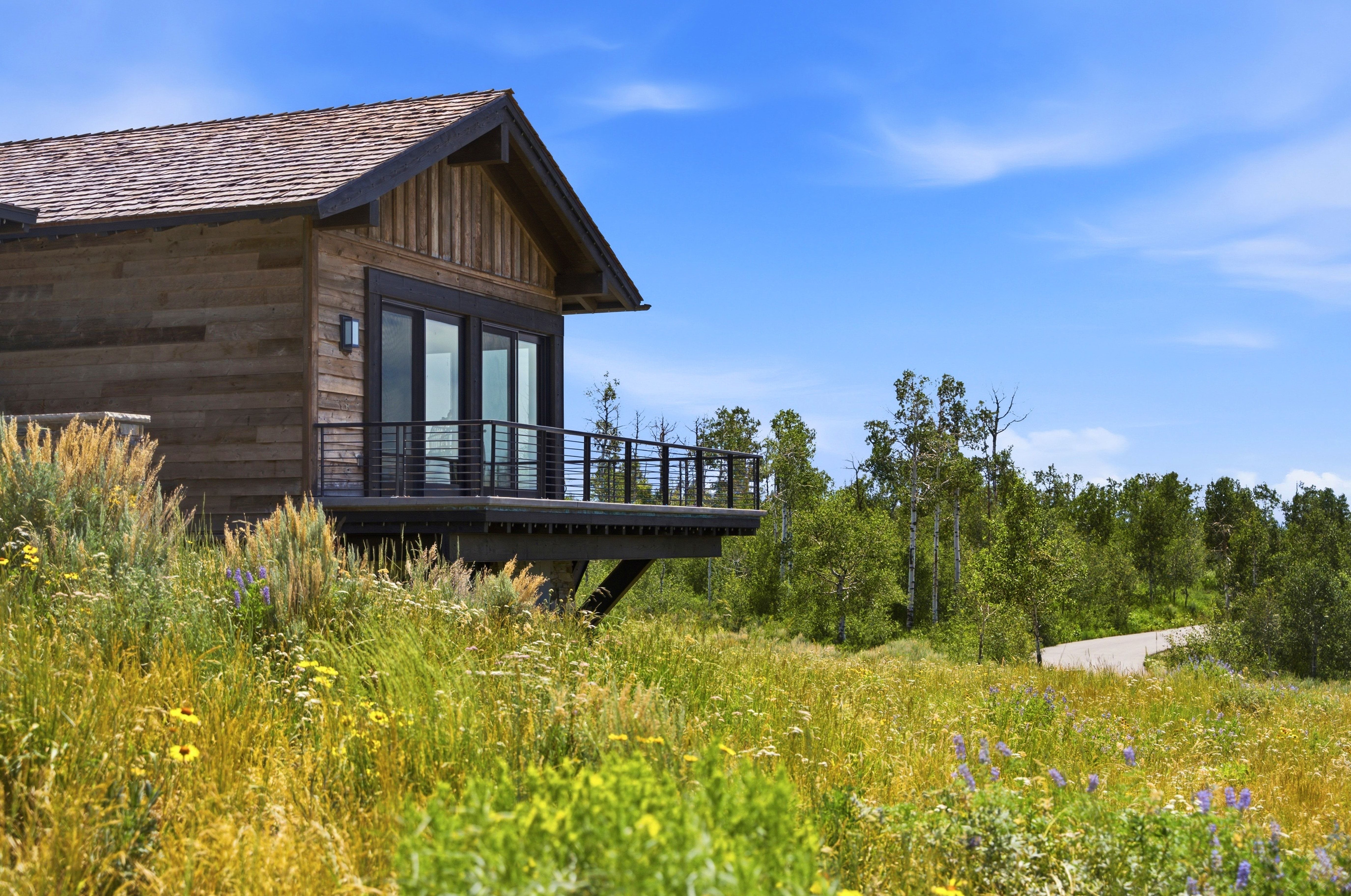 Wood-sided exterior featuring a shingle roof and a cantilevered deck with a black metal railing