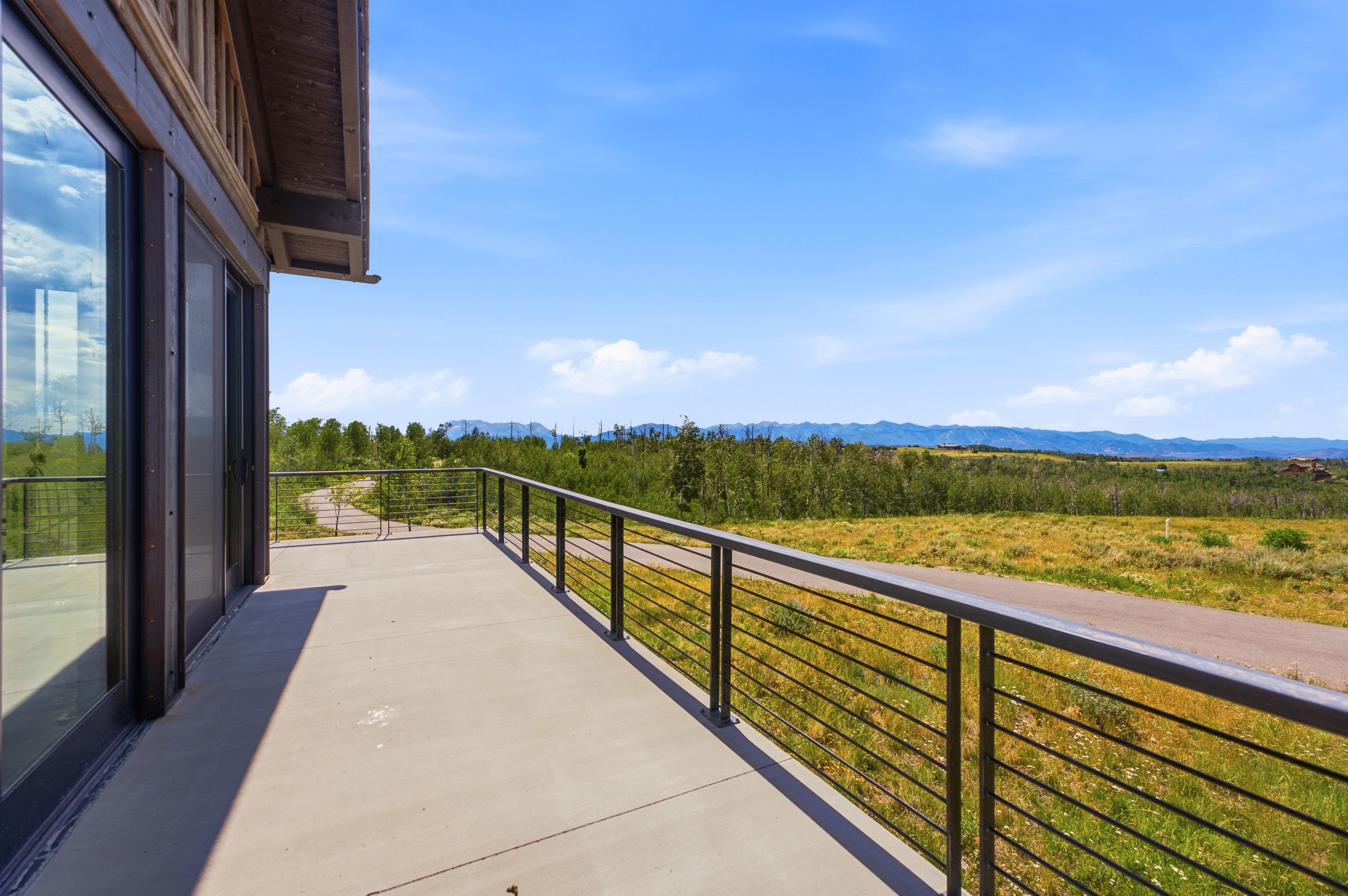 Expansive outdoor balcony featuring a concrete surface and cable railing