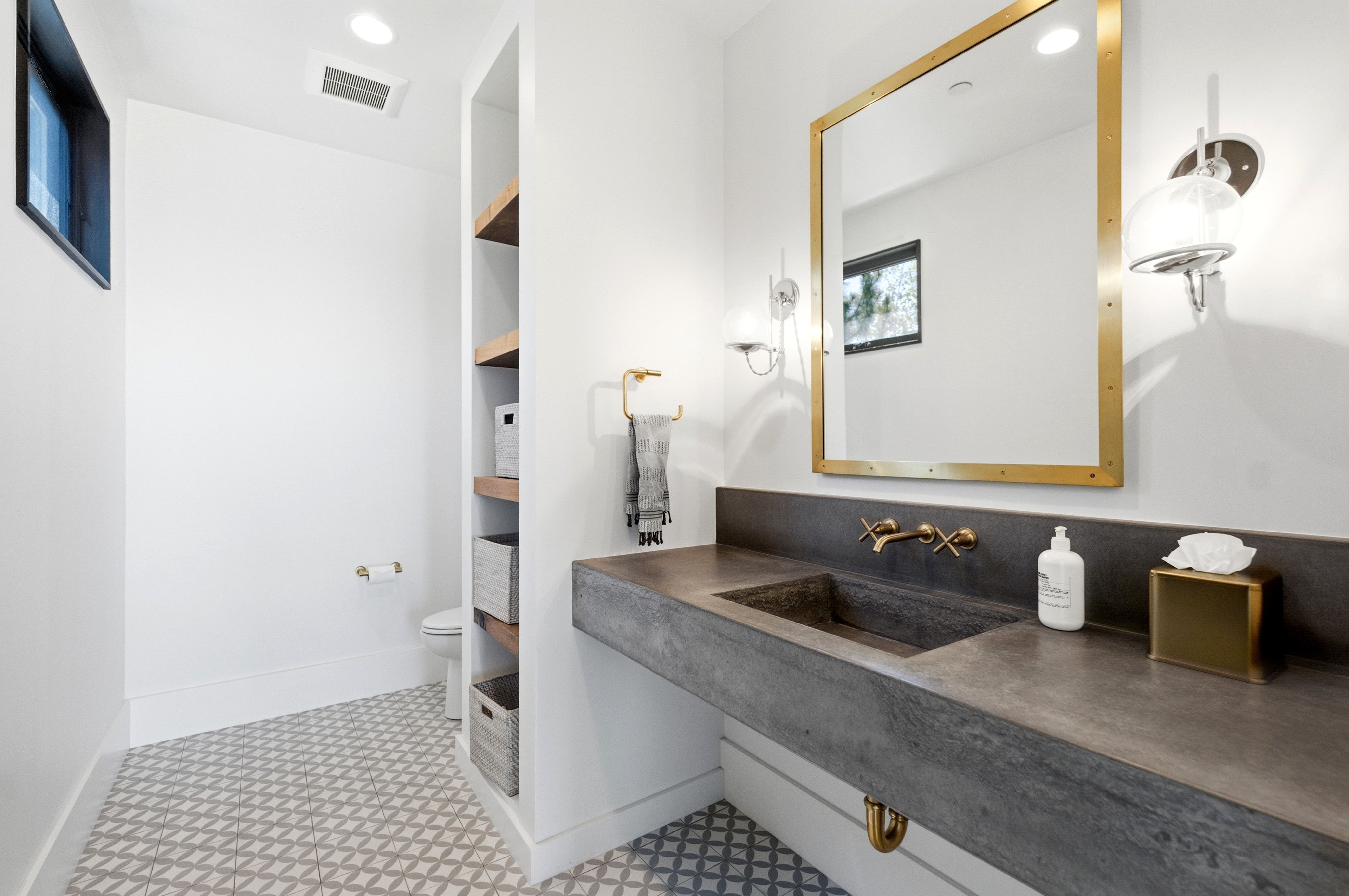 Modern vanity with integrated sink, wall-mounted brass faucet, and gold-framed mirror