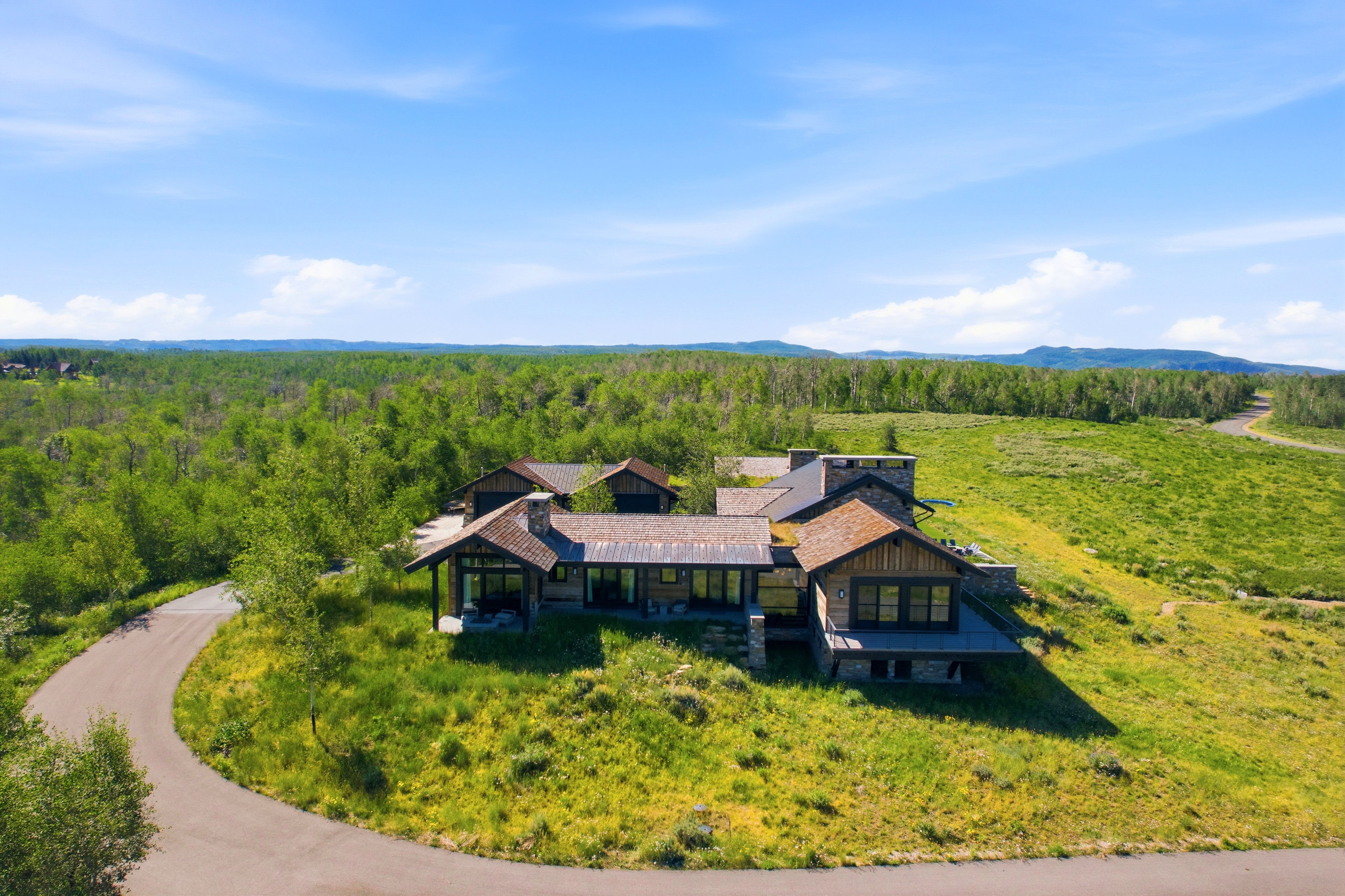 Expansive custom residence featuring multiple gabled rooflines, stone and wood siding, and numerous large windows