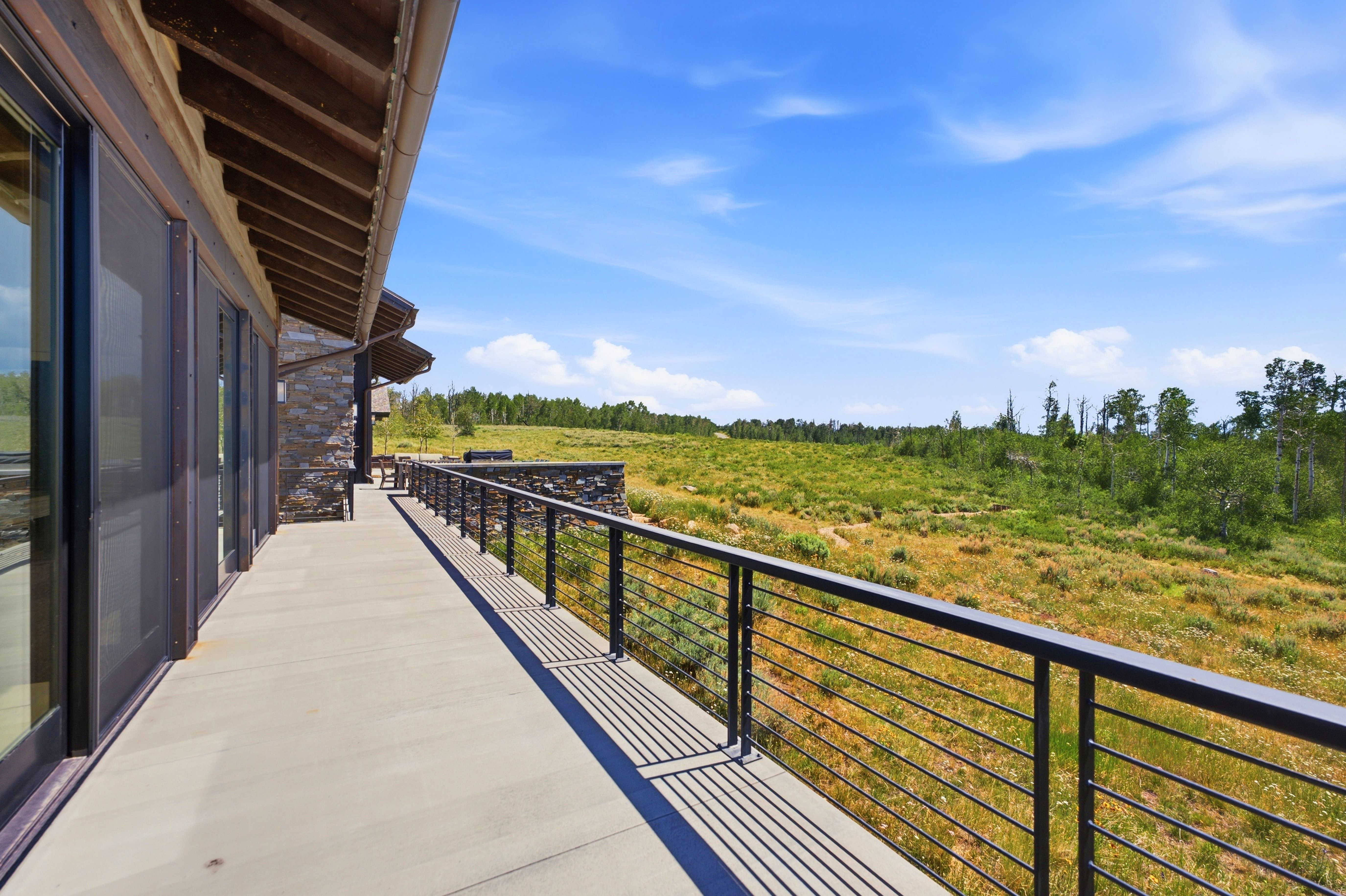 Spacious outdoor deck featuring a cable railing system and stone retaining wall