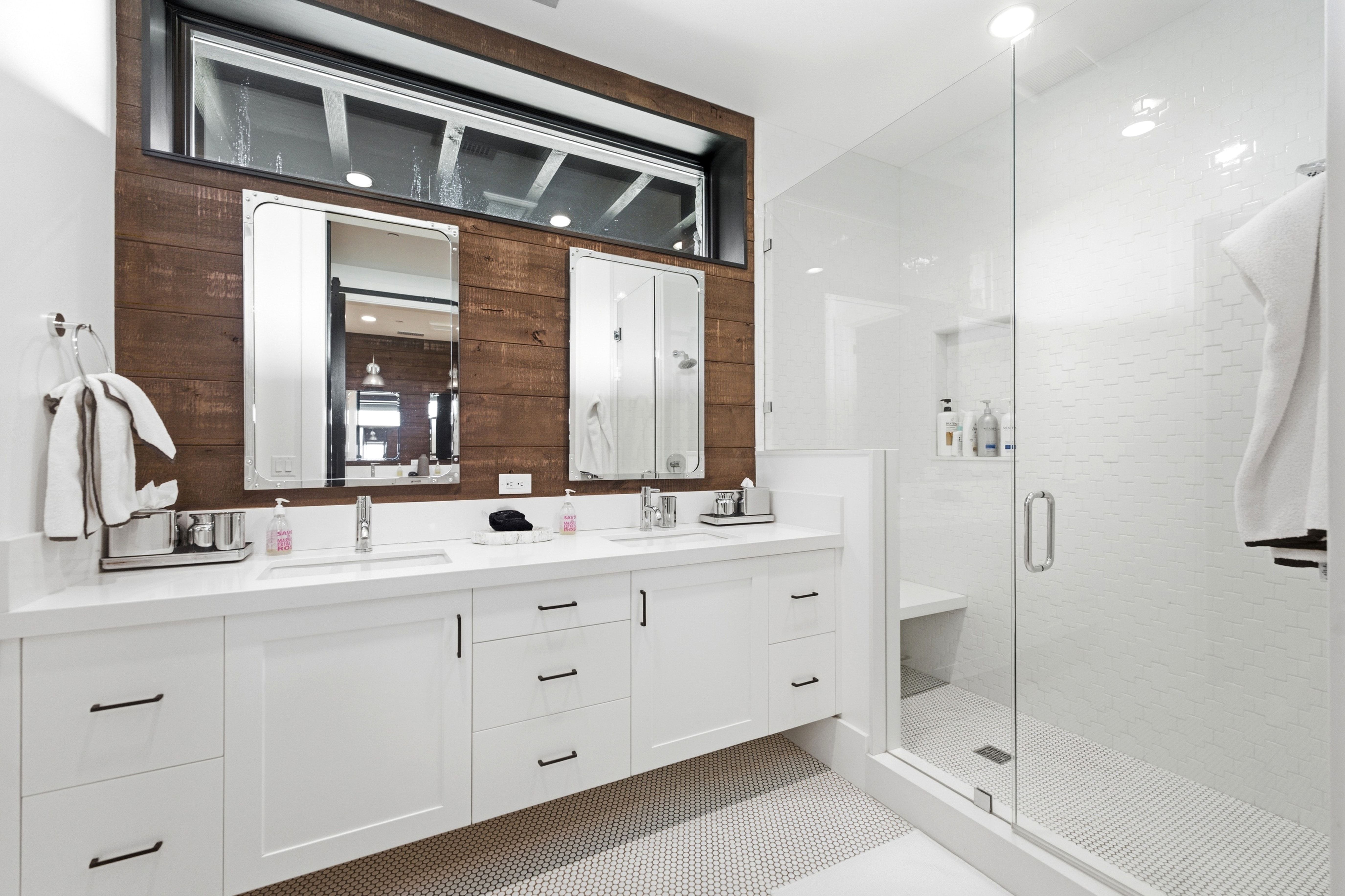 Dual vanity with undermount sinks and white countertops, set against a dark wood-paneled accent wall