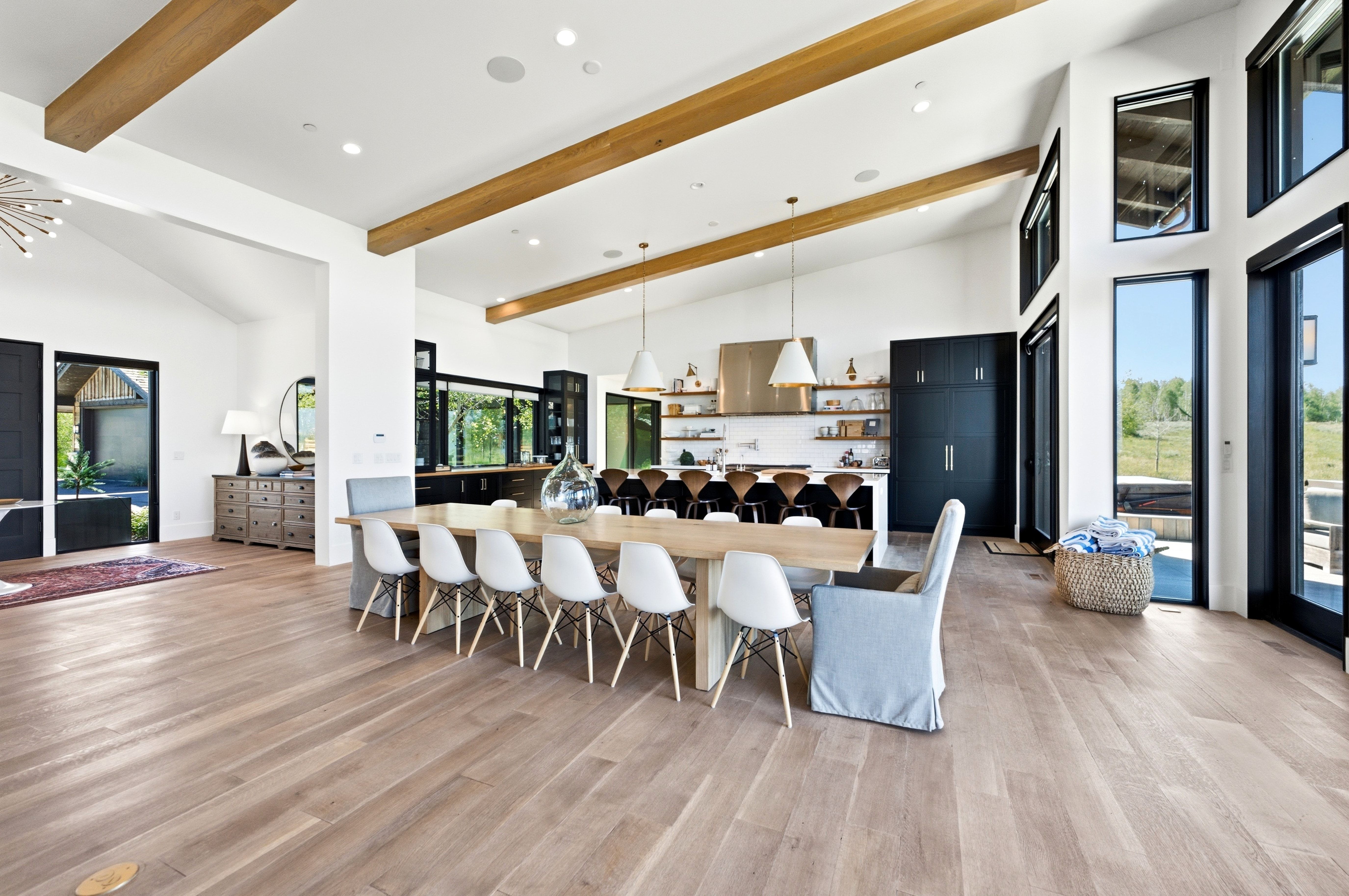 Open-concept living space featuring wood-finish flooring, exposed ceiling beams, and high ceilings