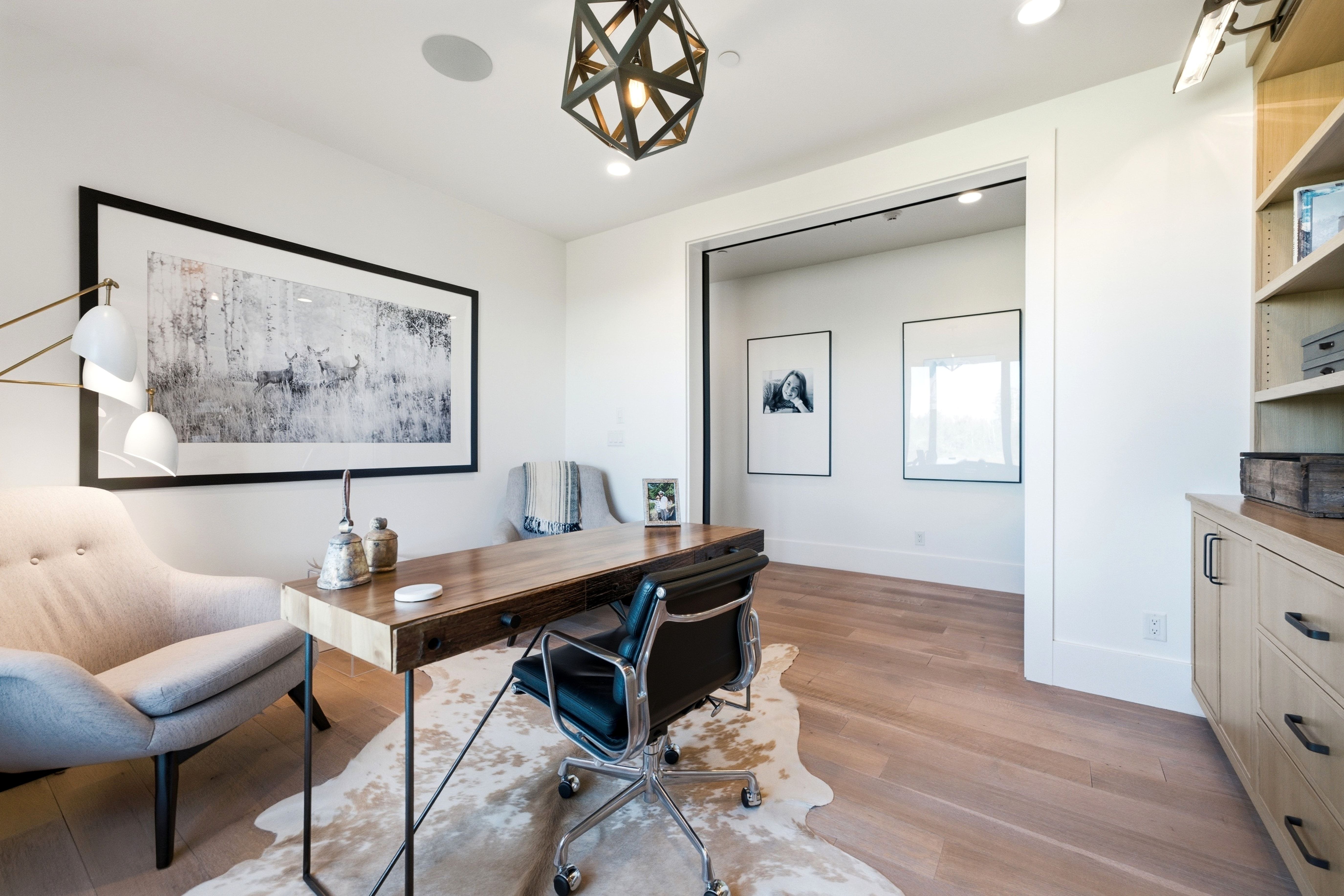 Open-concept office space featuring light wood-finish flooring and a geometric pendant light fixture