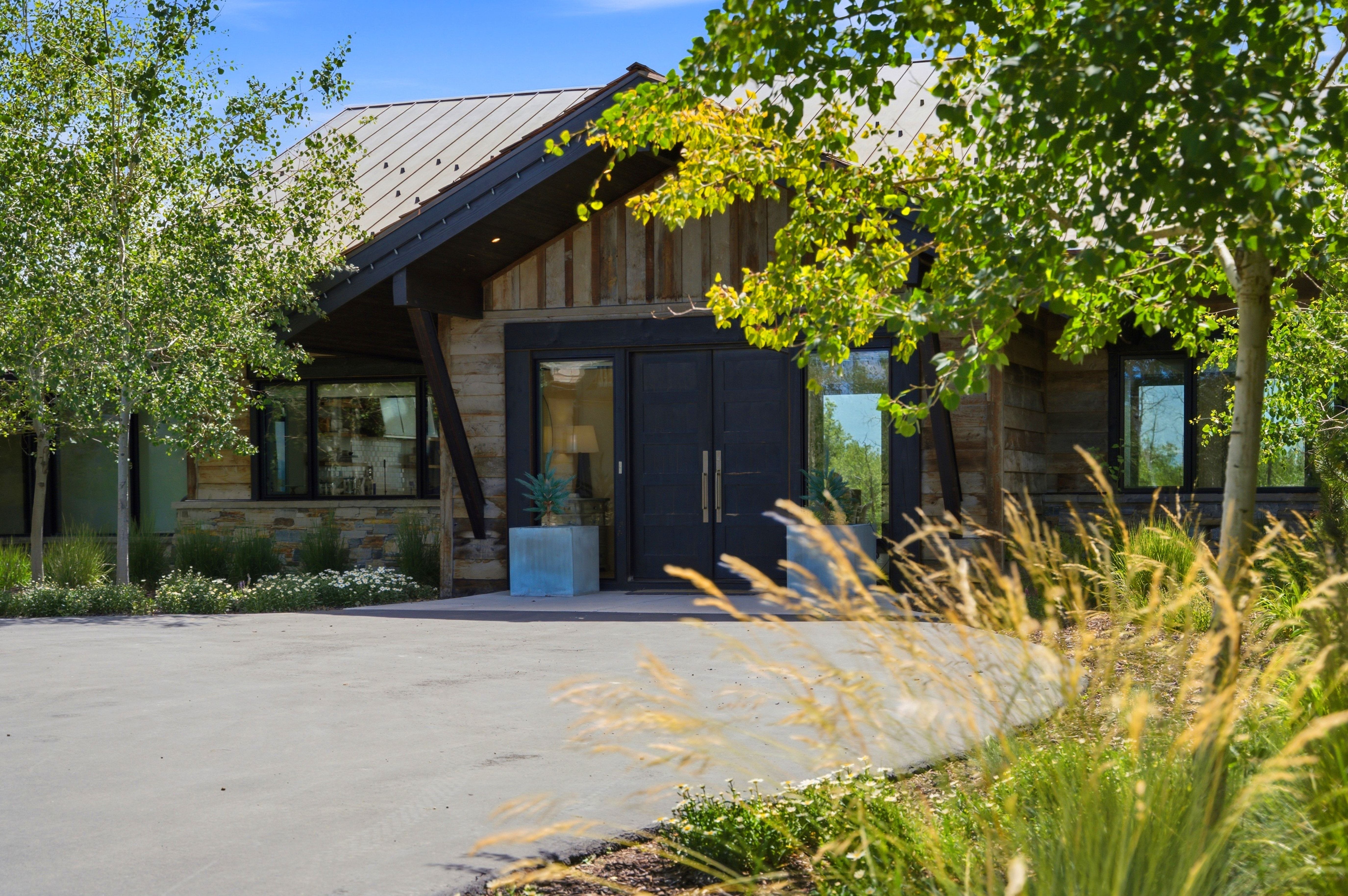 Contemporary residence featuring a striking metal roof, natural wood siding, and stone accents
