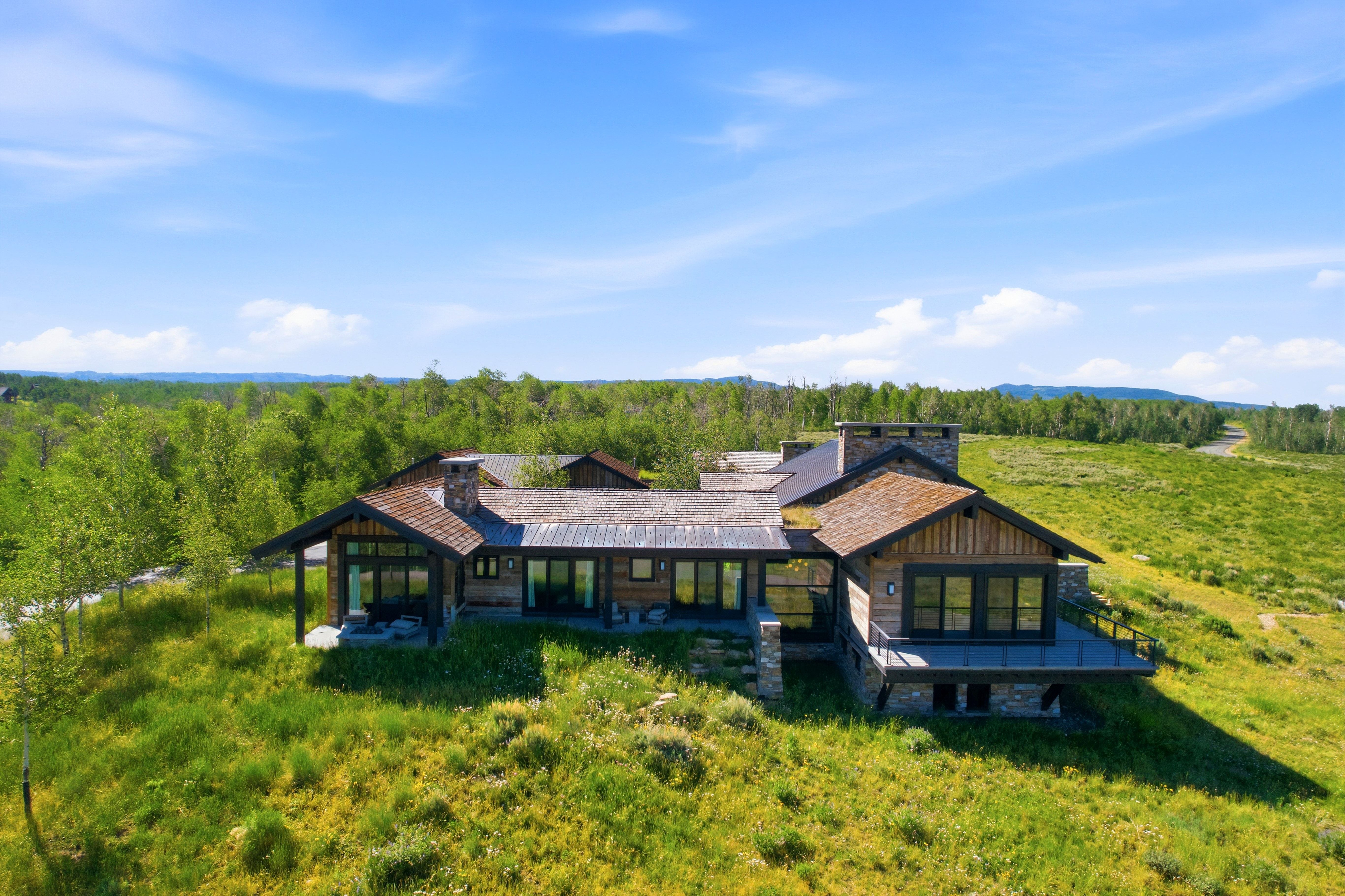 Contemporary mountain-style residence featuring a combination of wood siding, stone accents, and expansive window lines