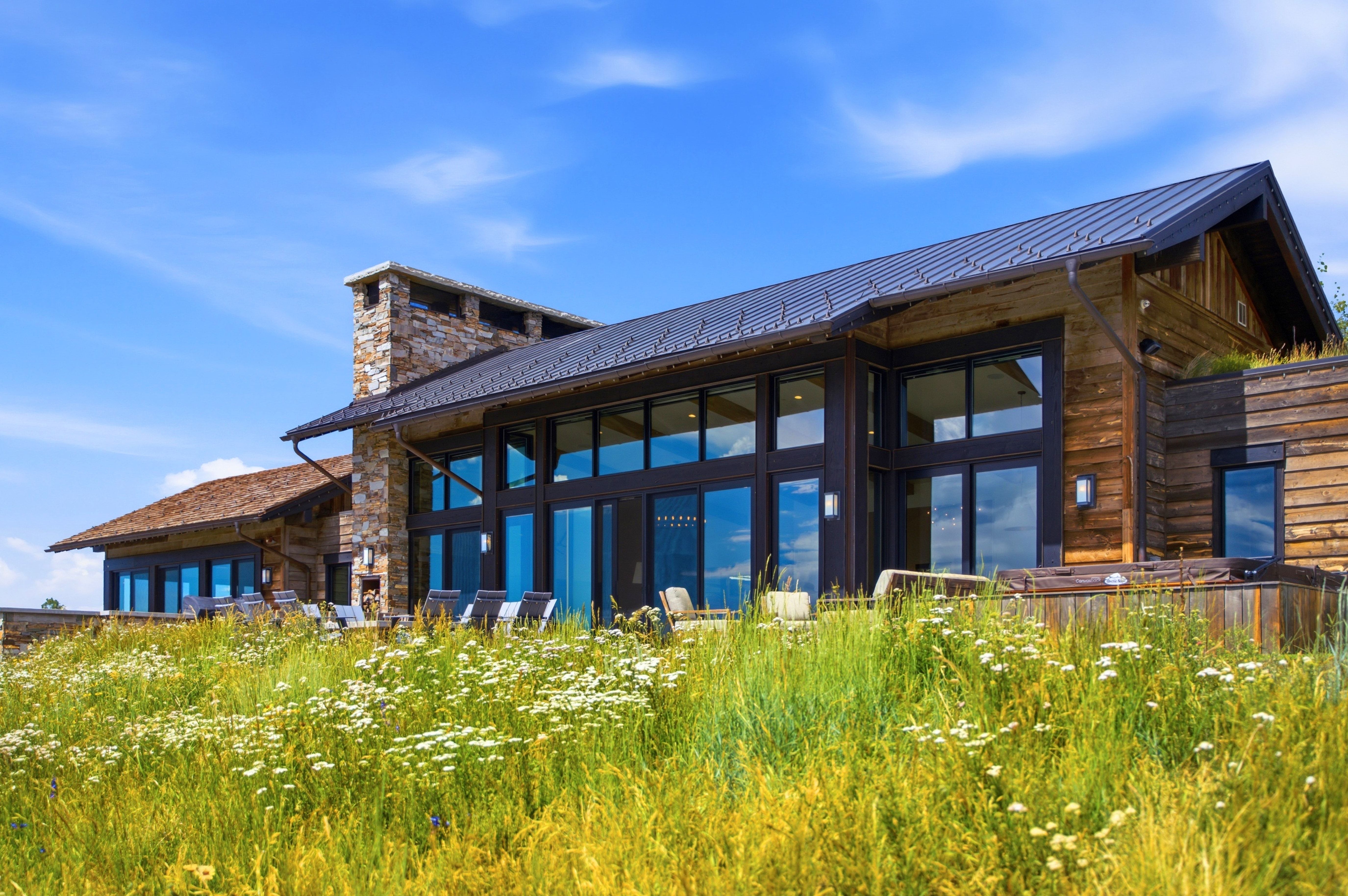 Contemporary exterior featuring a metal roof, stone chimney, and wood siding