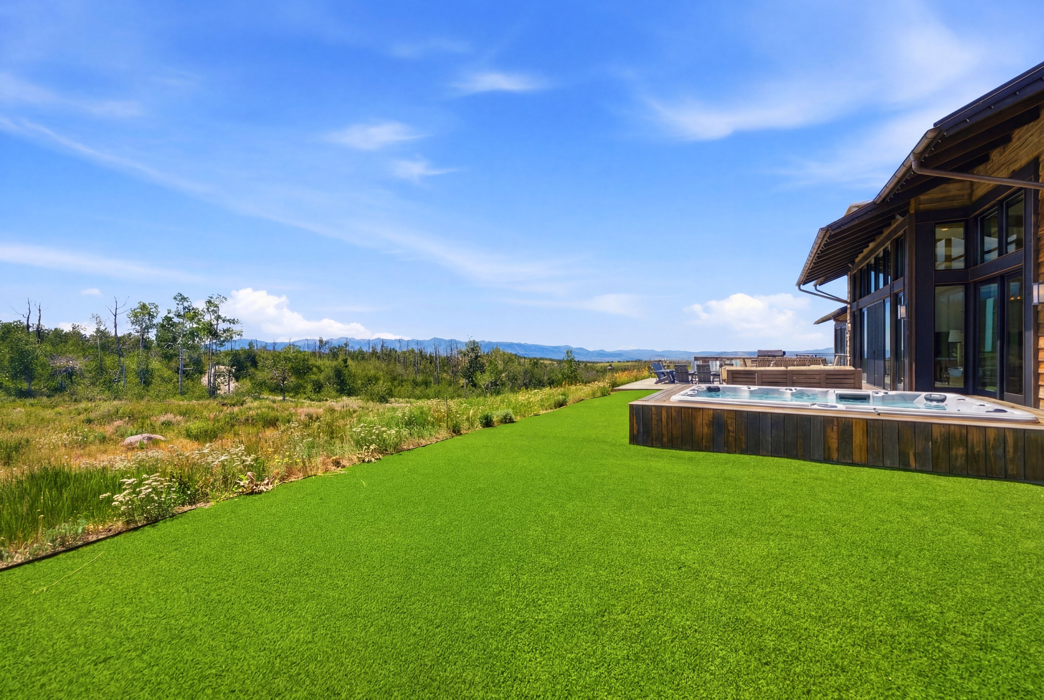 Expansive artificial turf lawn with a built-in hot tub, integrated into a wooden deck