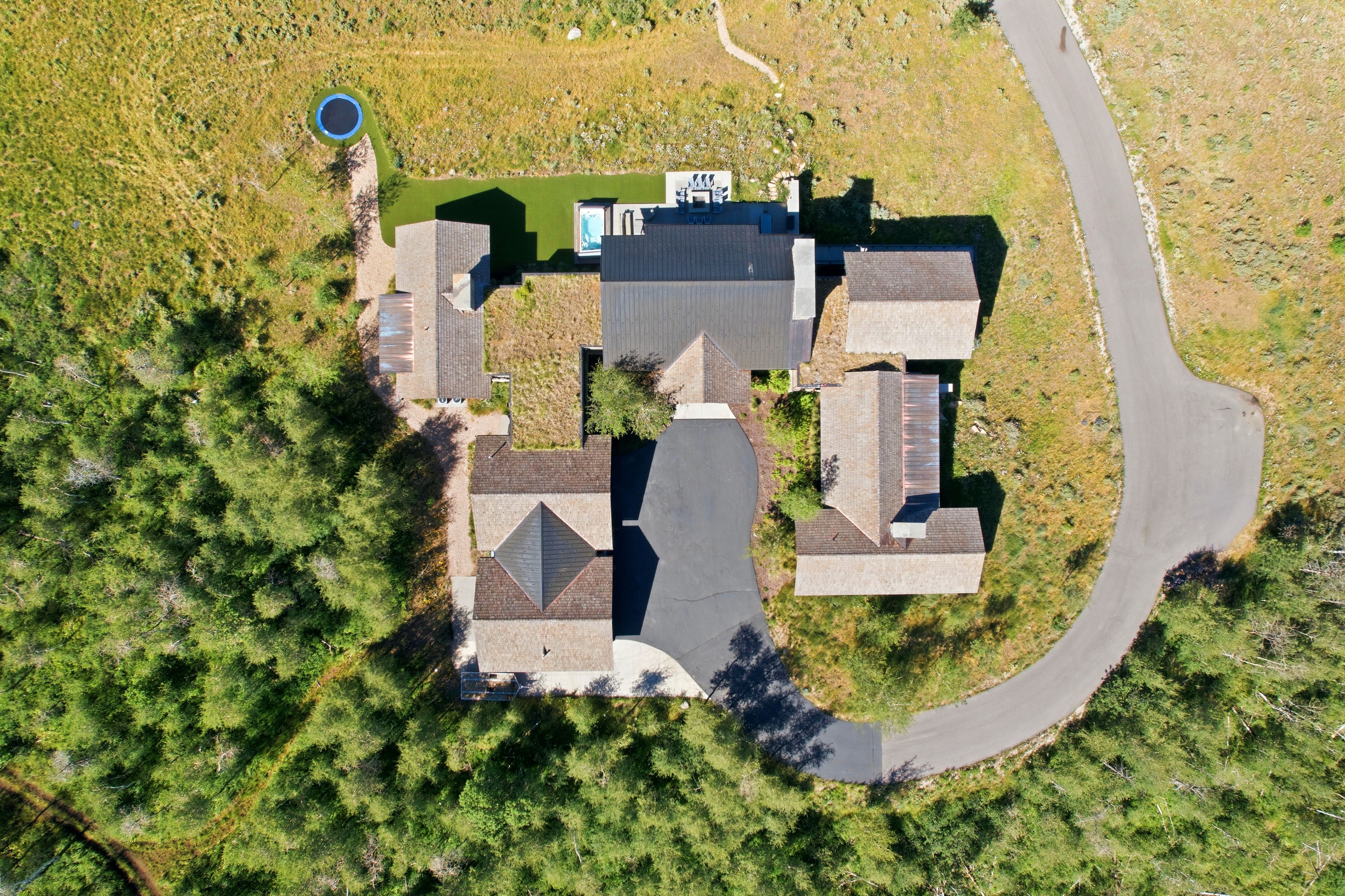 Expansive residential property with multiple structures, asphalt paving, and a swimming pool