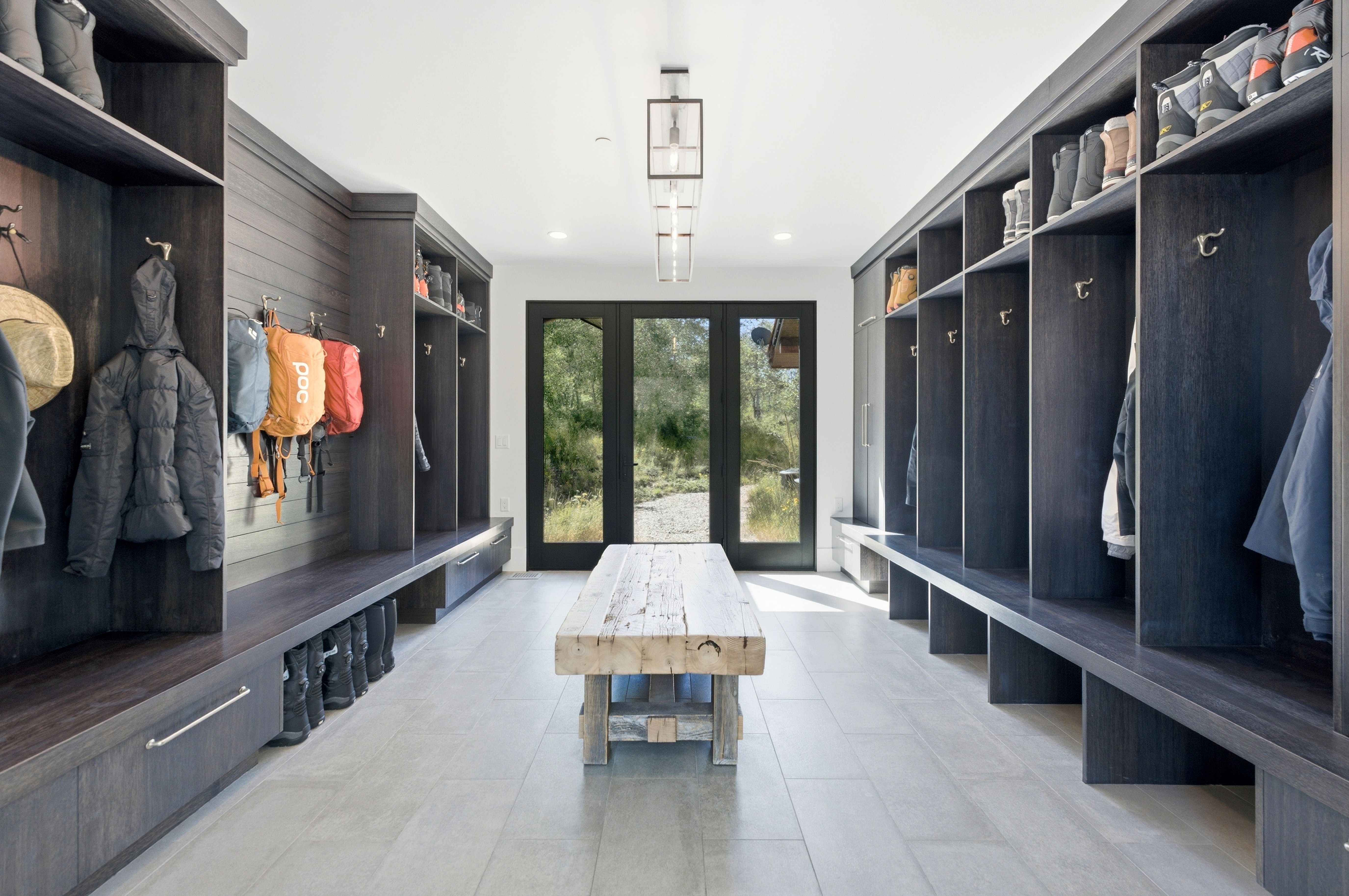 Spacious mudroom featuring extensive built-in cabinetry, individual cubbies with coat hooks, integrated benches, and ample storage