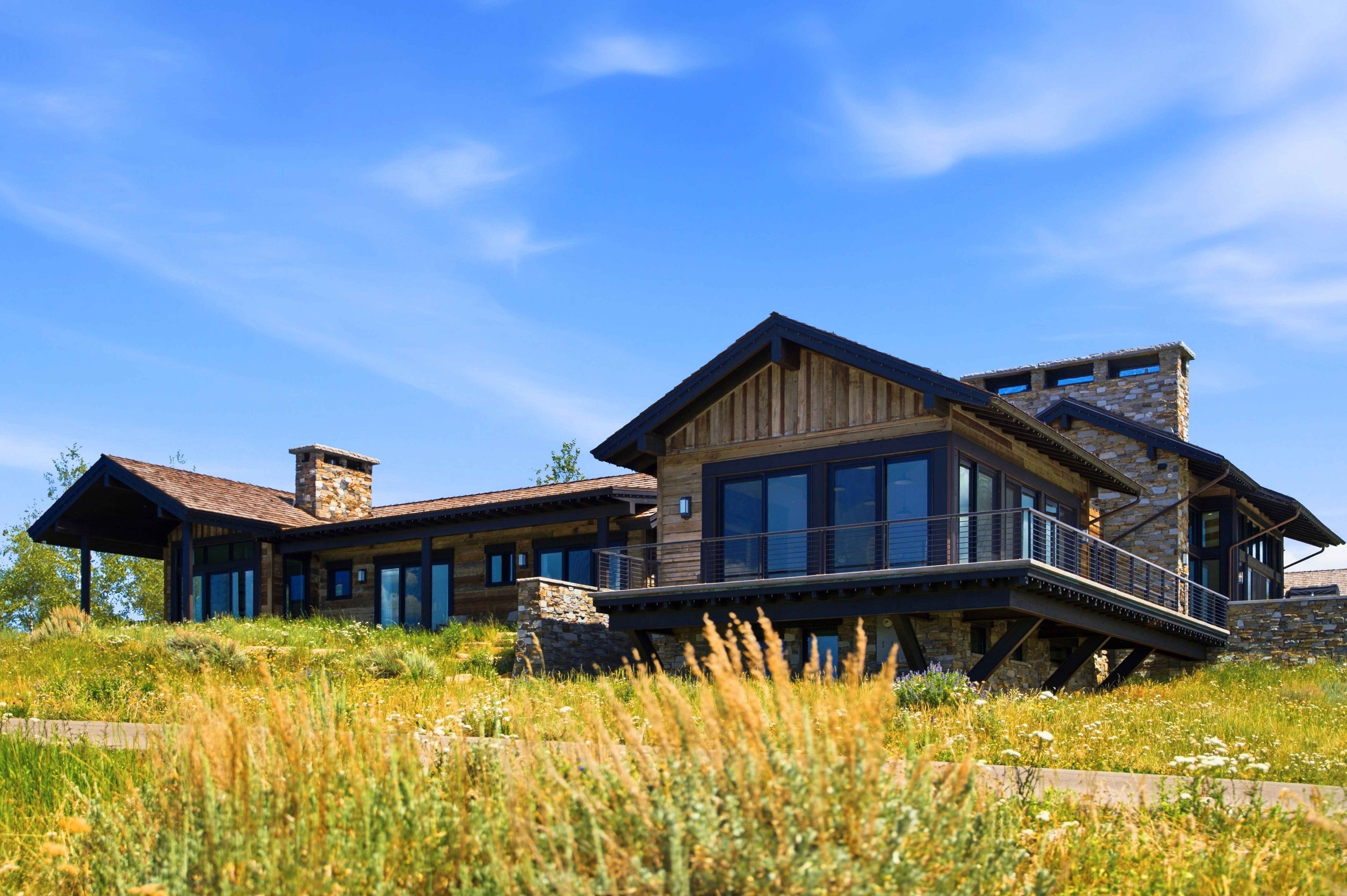 Contemporary ranch-style residence featuring a wood-panel exterior, stone accents, and a low-sloping roofline