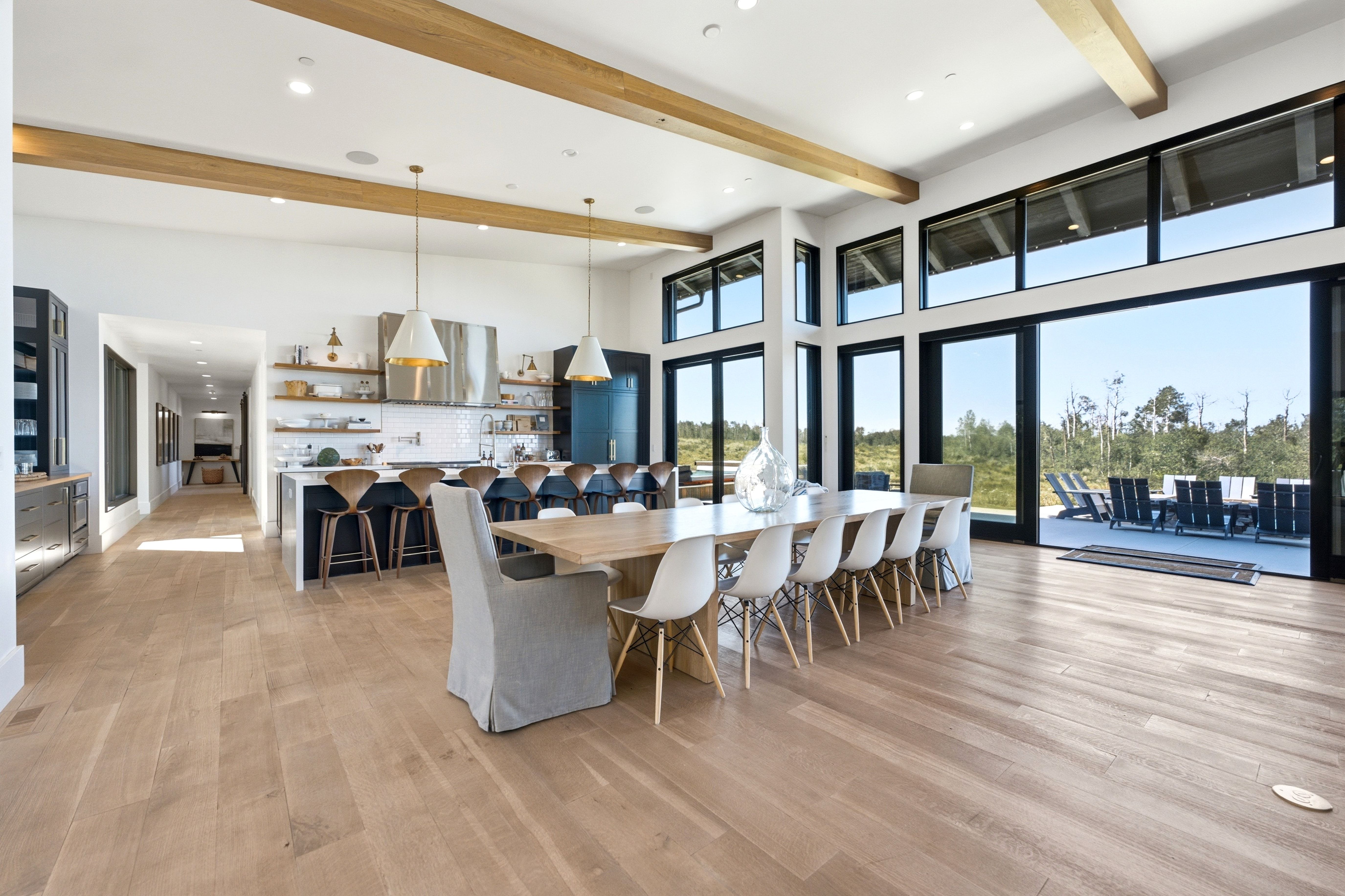 Spacious open-concept living area featuring light wood-finish flooring and exposed wood beams