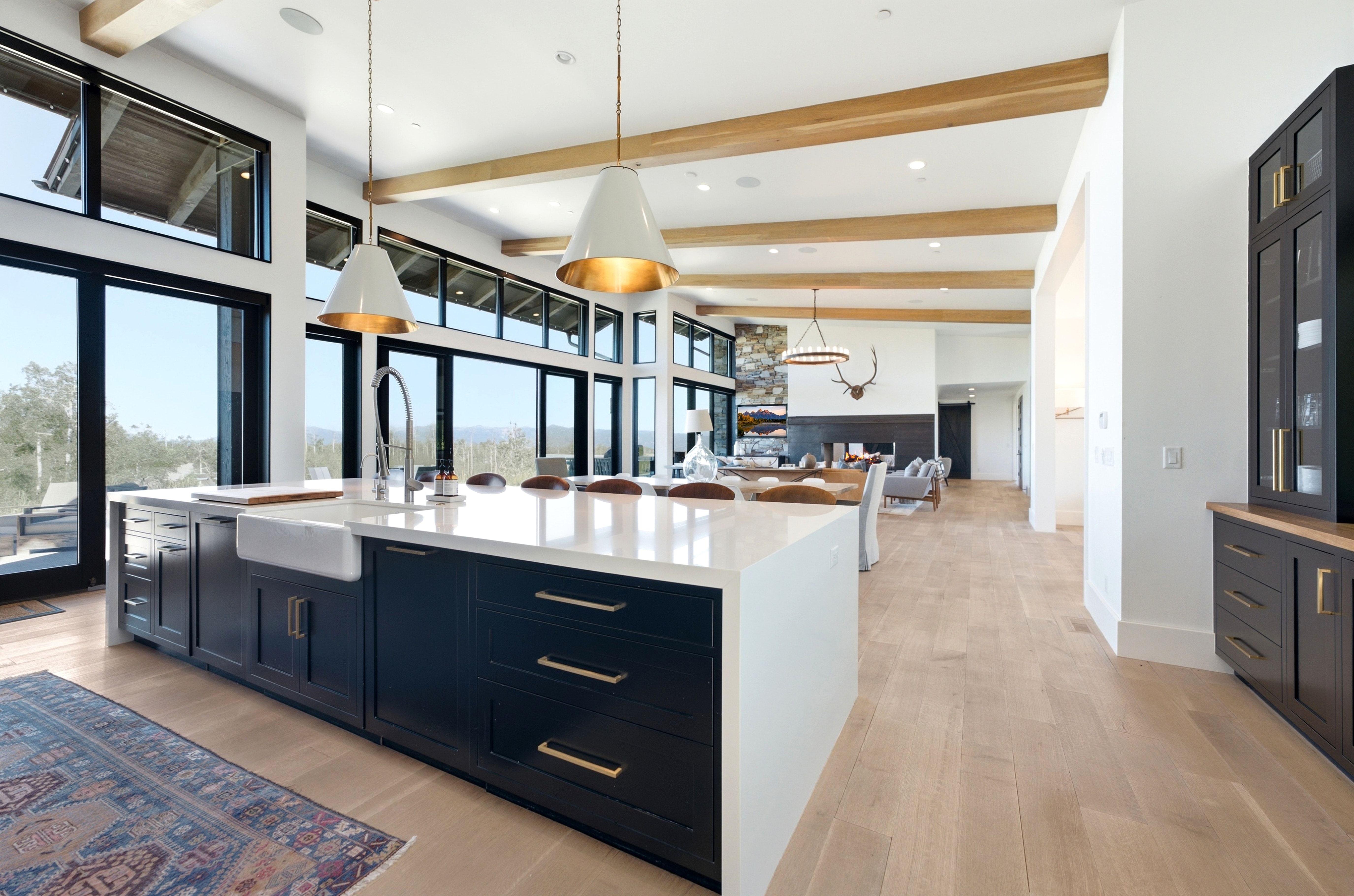 Gourmet kitchen island featuring a farmhouse sink, stone countertop, and custom dark cabinetry