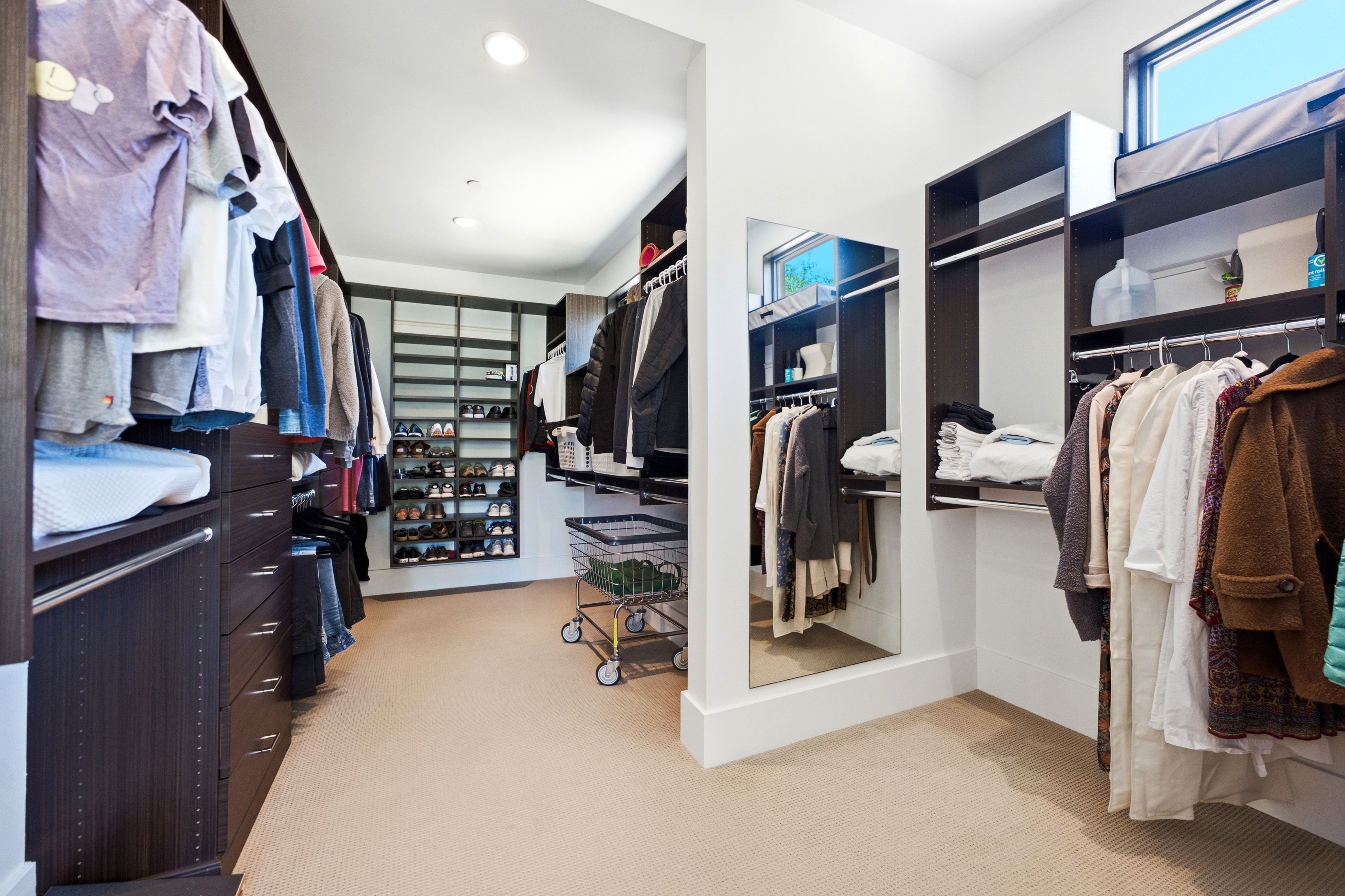 Spacious walk-in closet featuring extensive built-in shelving, dark wood-finish cabinetry, recessed lighting, and a full-length mirror