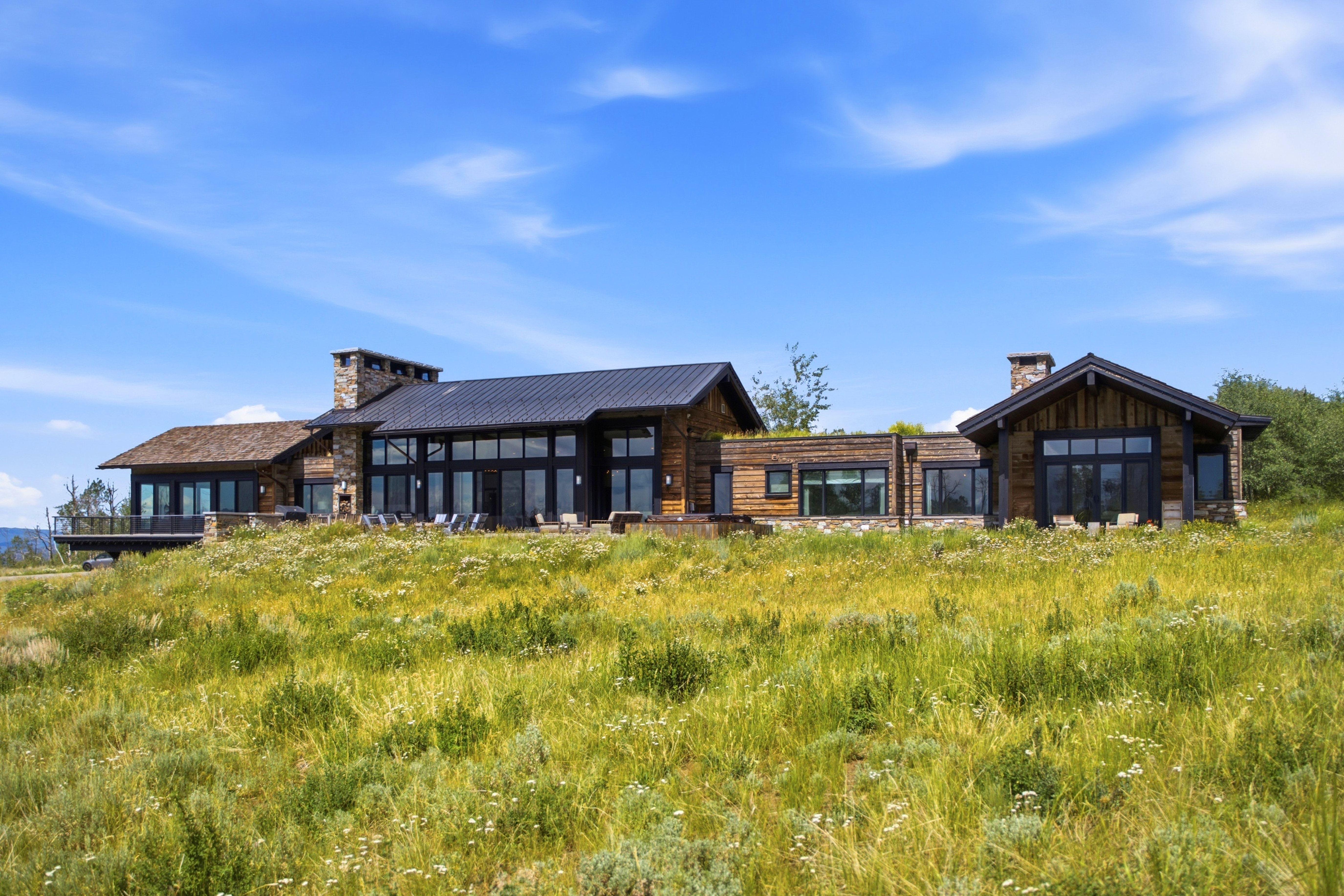 Expansive rustic modern residence featuring wood siding and a metal roof