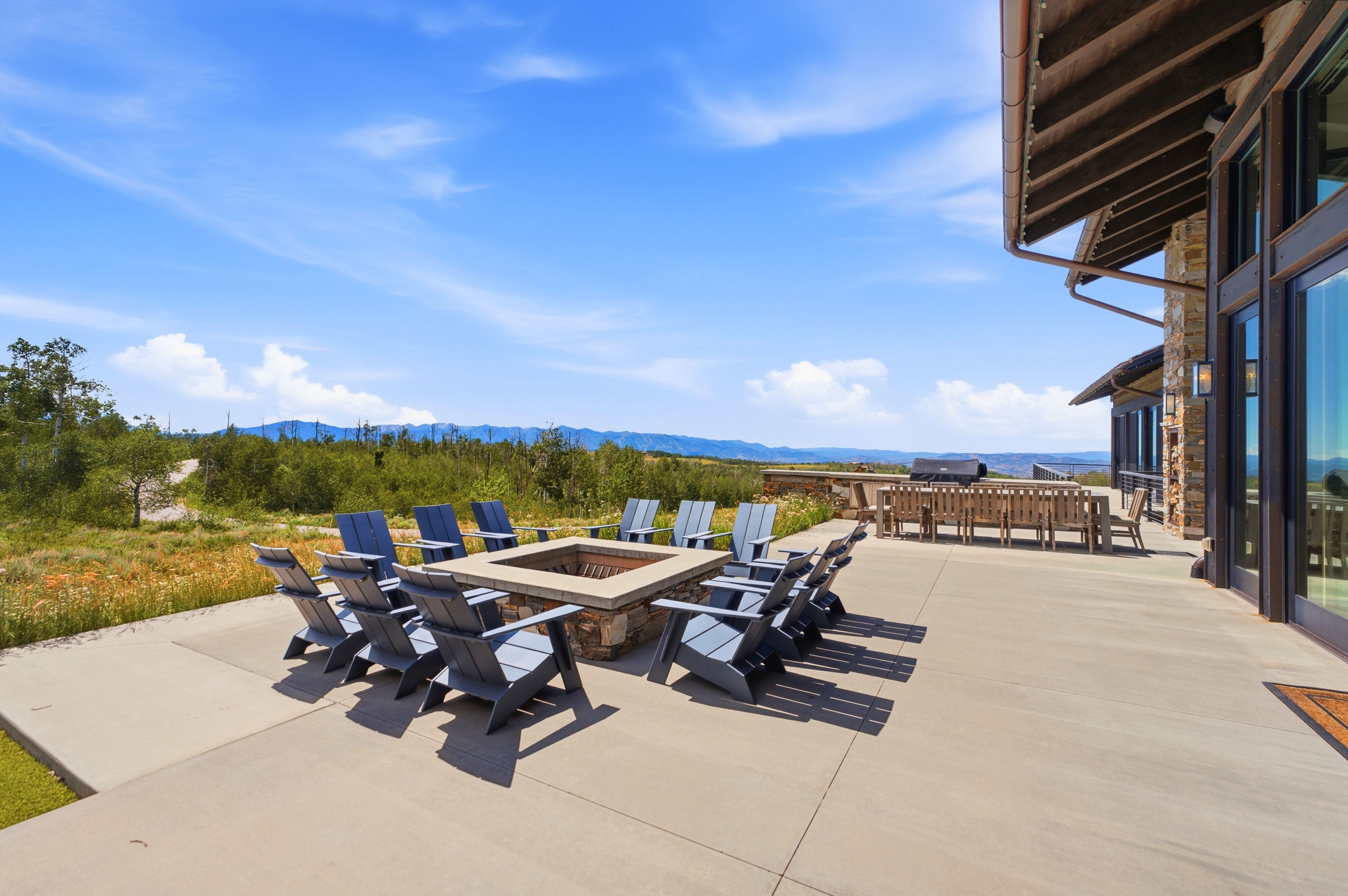 Expansive concrete patio featuring a stone-clad fire pit