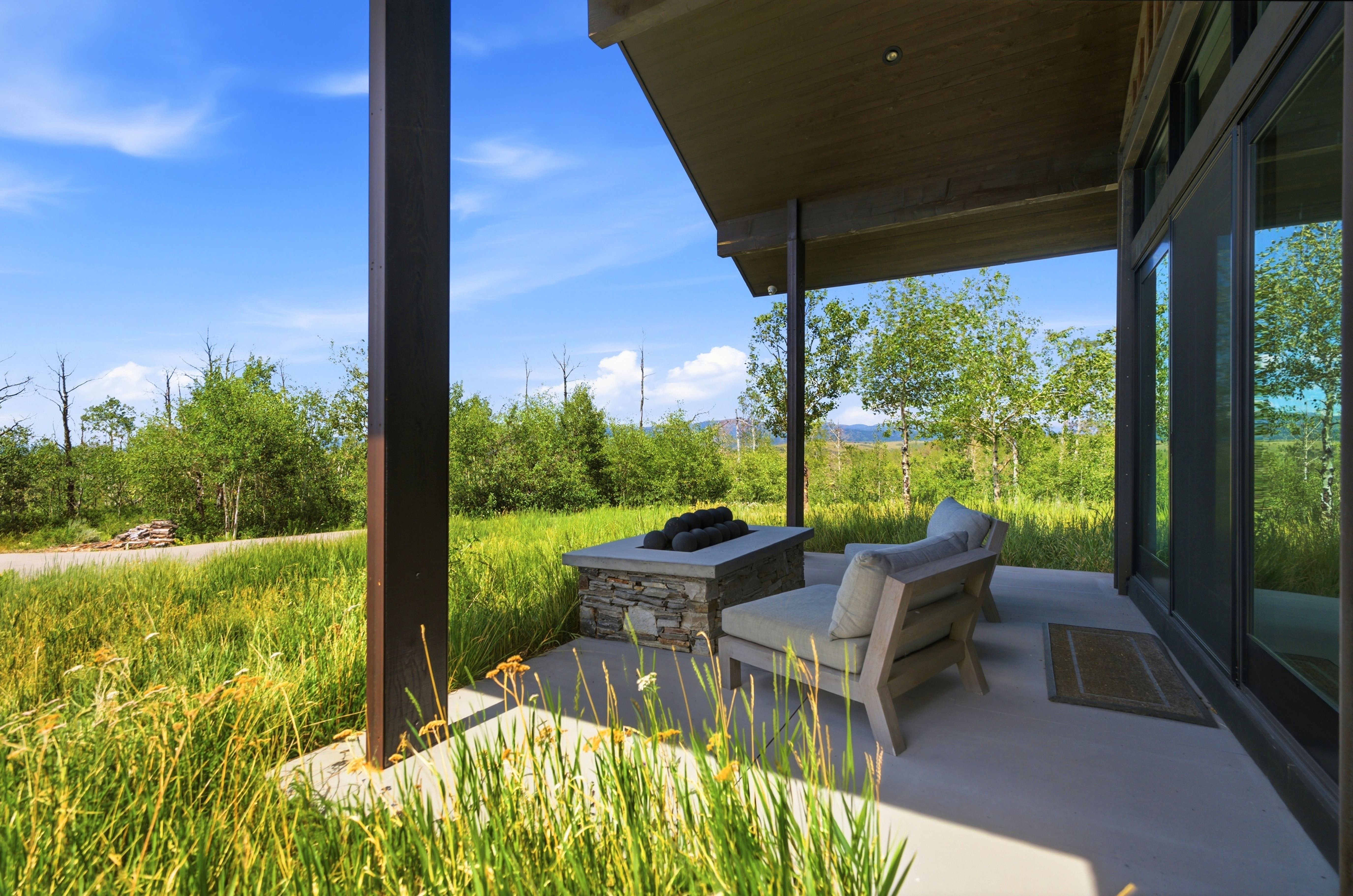 Covered patio featuring a built-in stone fire pit, concrete flooring, and a flat roofline