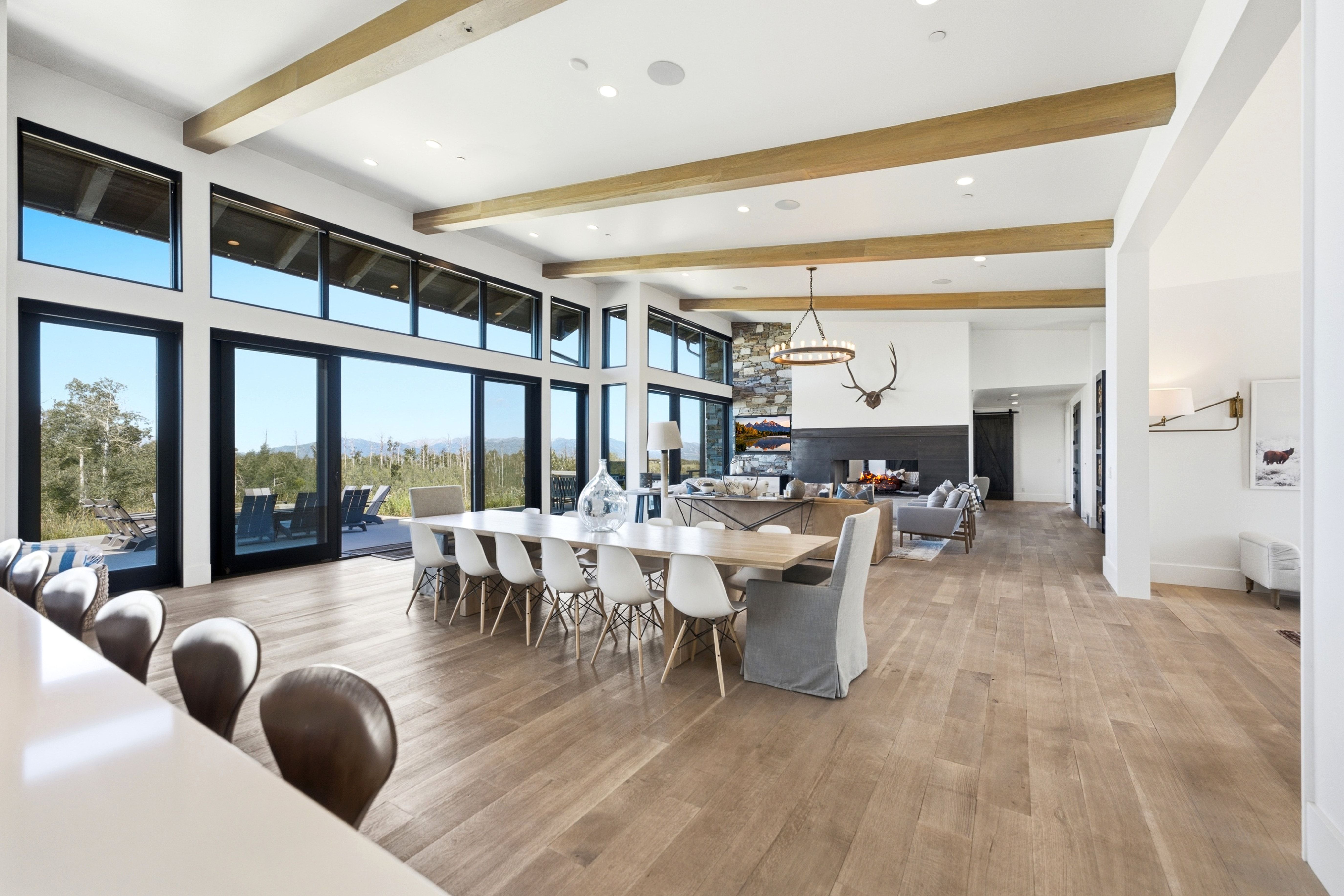 Expansive open-concept interior featuring wood-finish flooring, exposed ceiling beams, a stone accent wall, and a fireplace with a black hearth