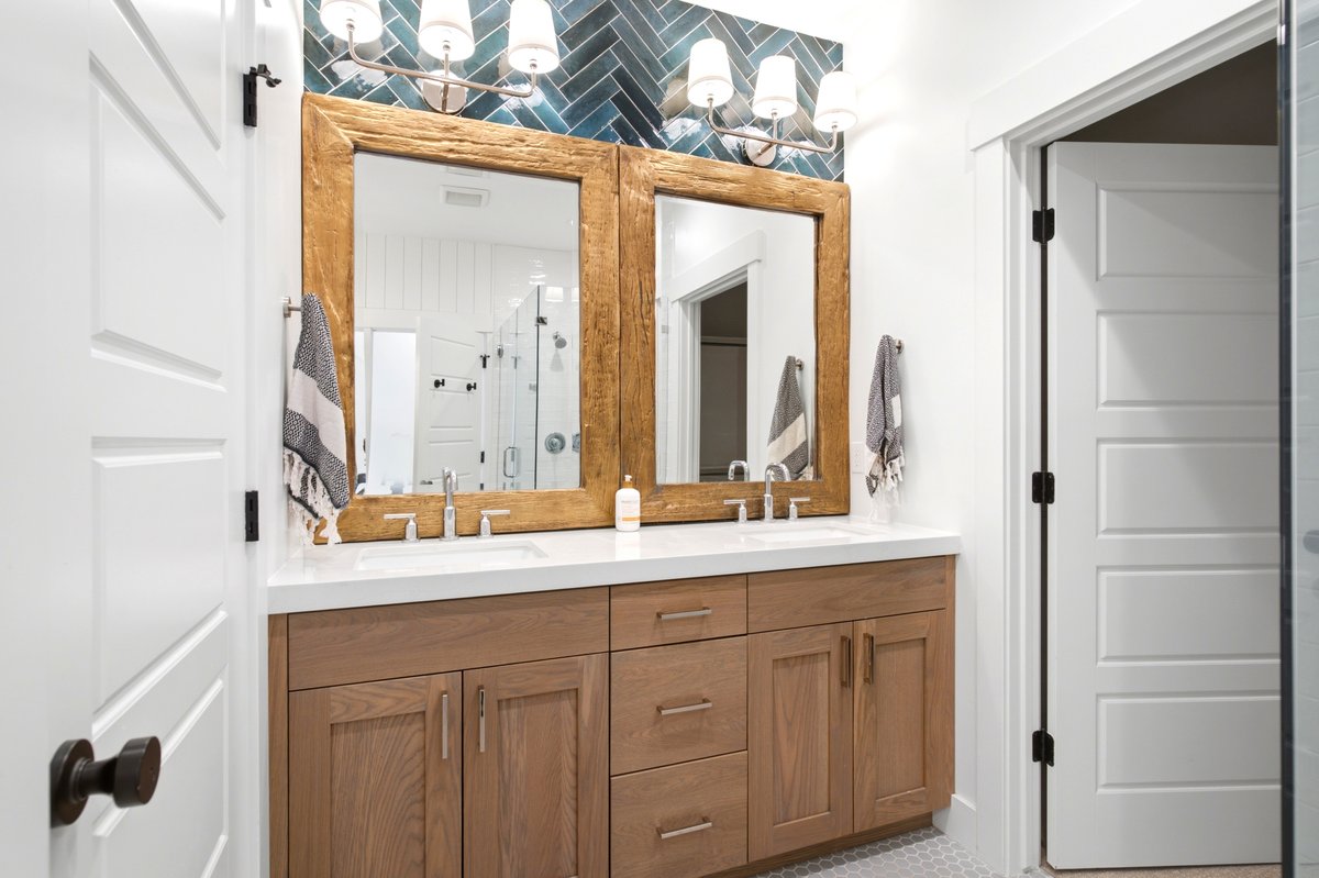 Double vanity featuring light wood-finish cabinetry, white countertops, and dual vessel sinks with chrome fixtures