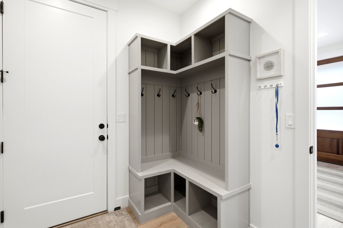 Built-in custom mudroom storage featuring a bench, shelving, and coat hooks