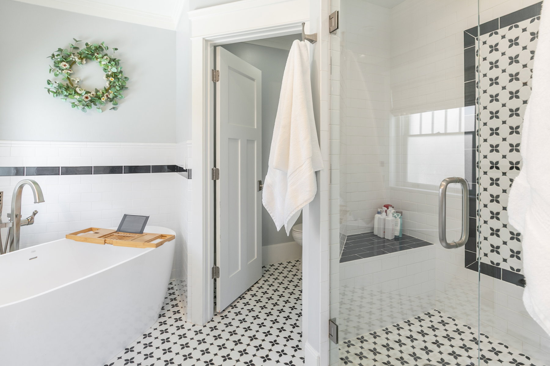 Bathroom featuring a freestanding soaking tub with floor-mounted faucet, a walk-in shower with glass enclosure, and a tiled shower bench