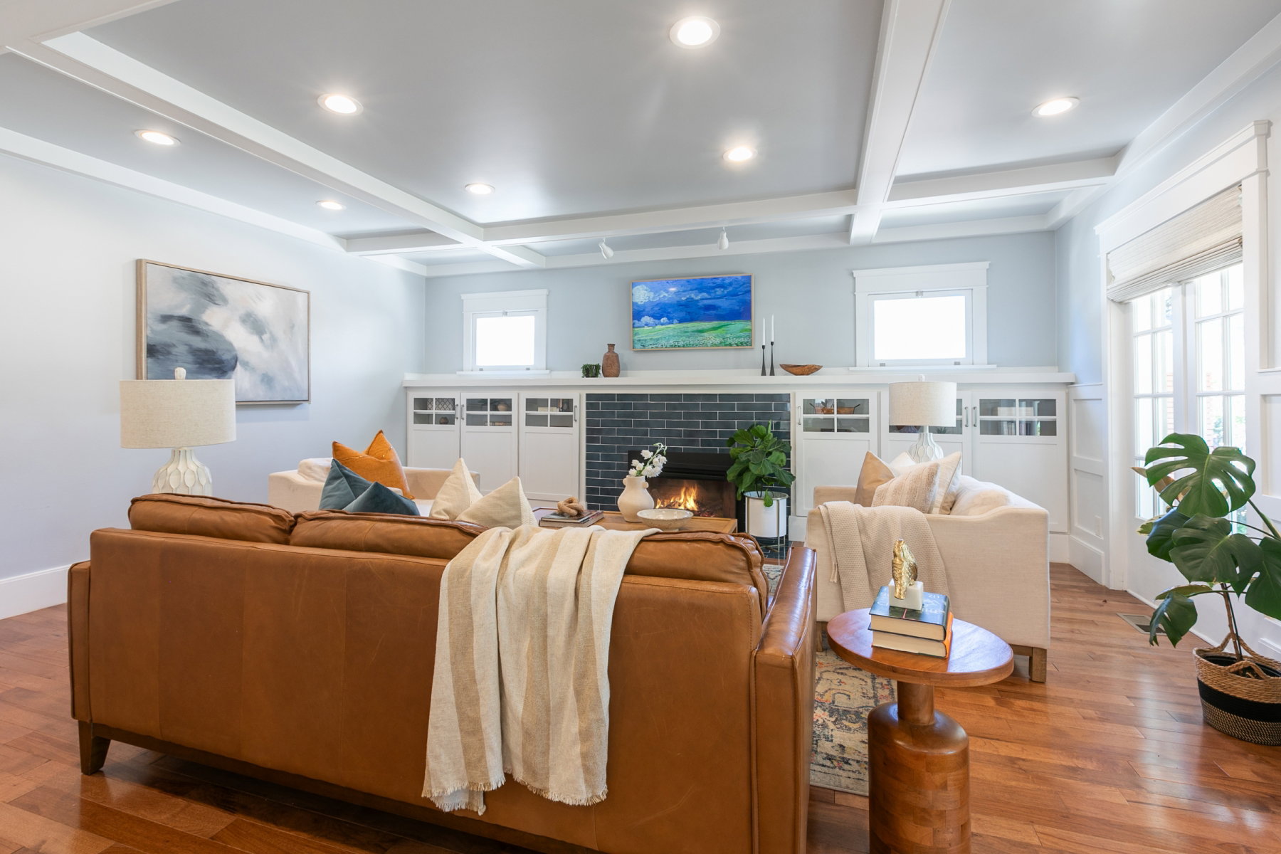 Living area featuring hardwood flooring, a fireplace with dark tile surround, built-in cabinetry, coffered ceilings, and recessed lighting