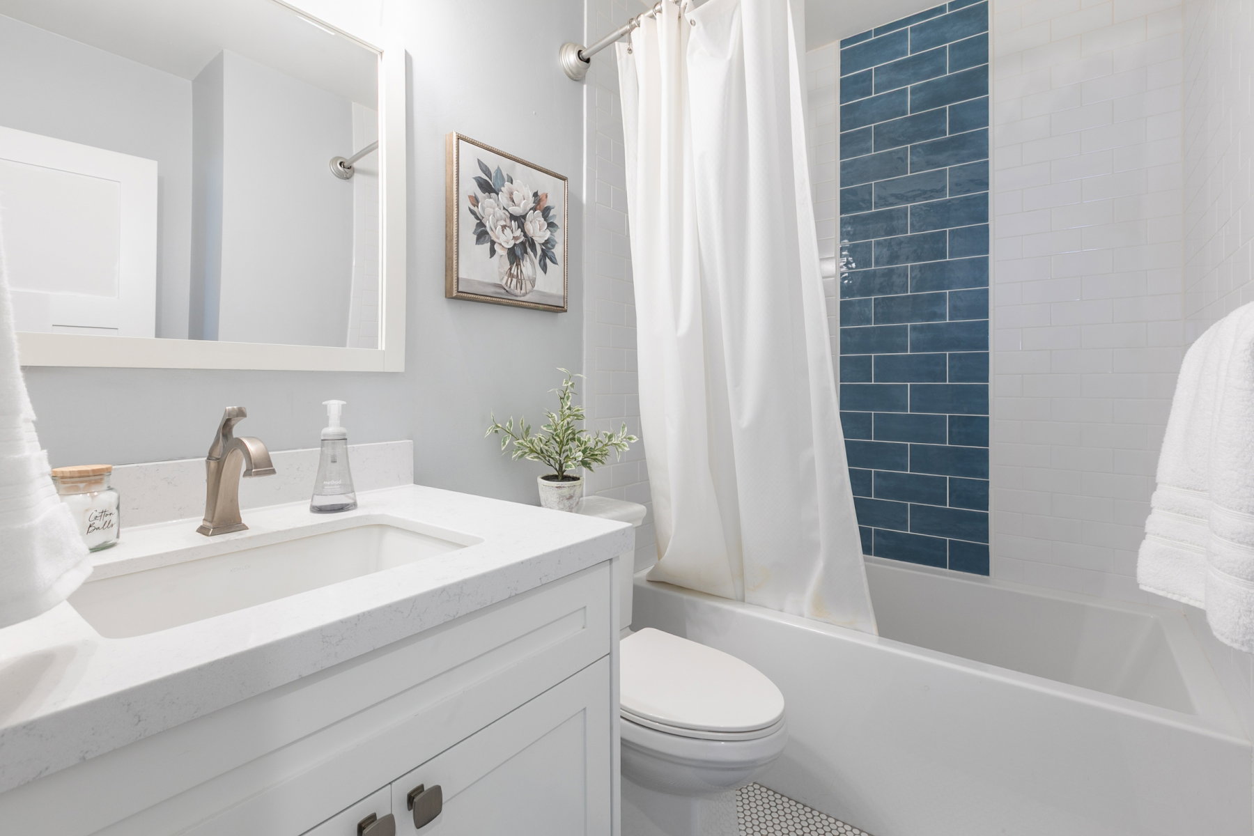 Bathroom featuring a white vanity with an integrated sink, brushed bronze faucet, and a quartz countertop