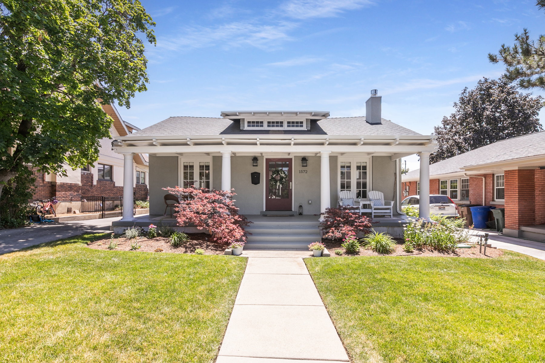 Craftsman-style home featuring a covered front porch with substantial columns, a dark wood entry door, and a prominent chimney