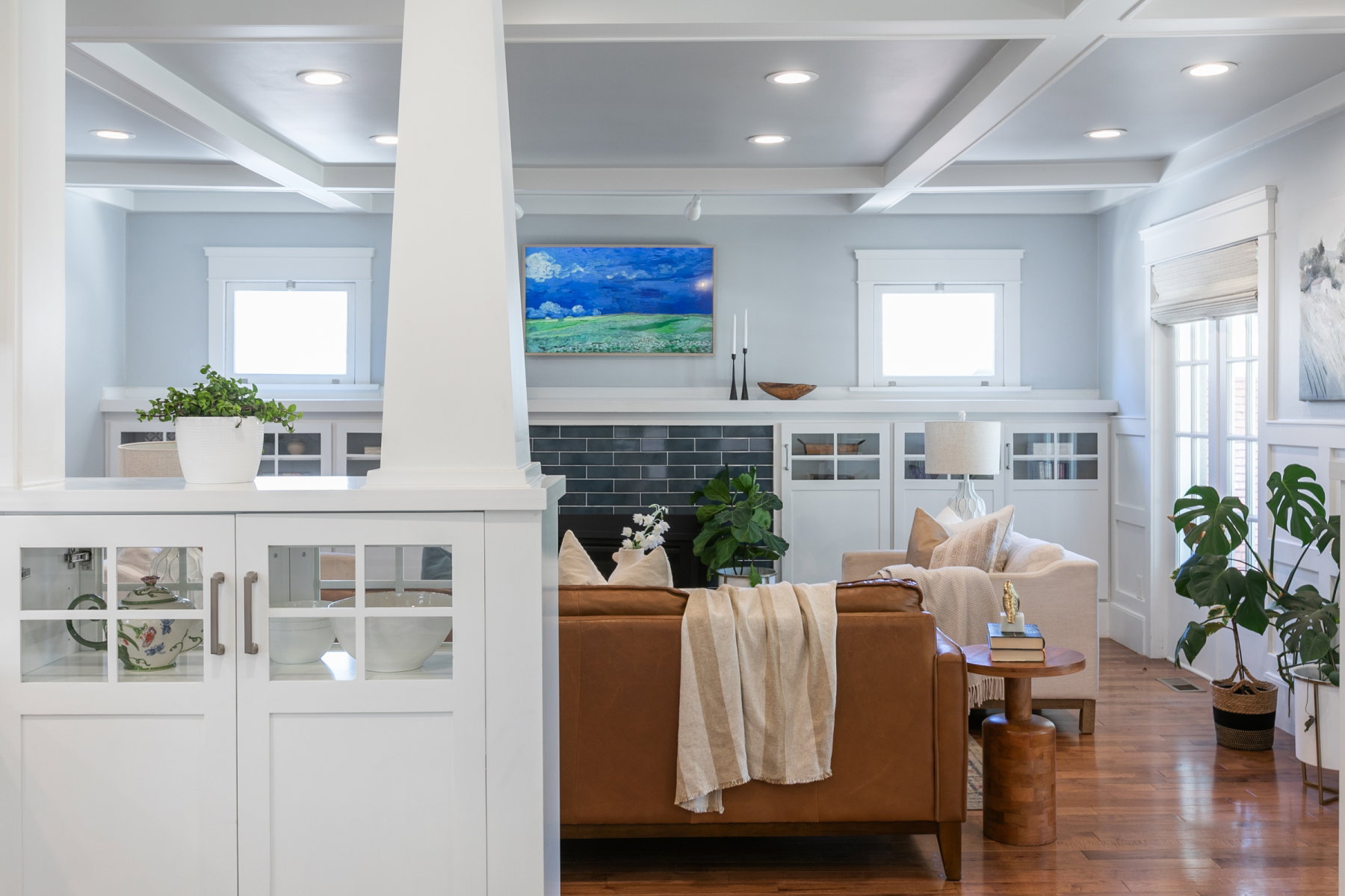 Living area featuring wood-finish flooring, a coffered ceiling with recessed lighting, and white built-in cabinetry with glass-paneled doors