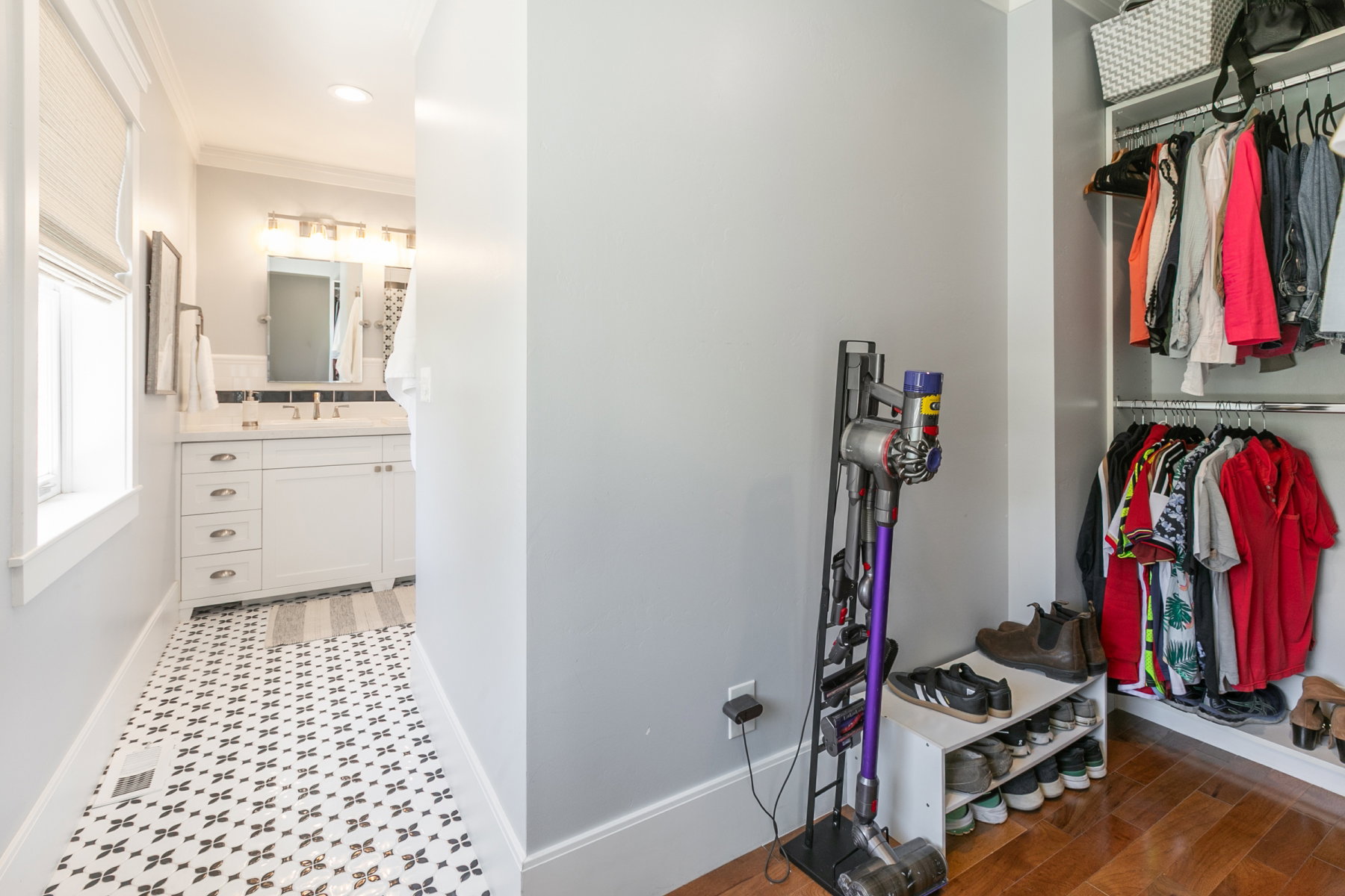 Bright bathroom featuring a single vanity with a white countertop and dark tile backsplash, decorative floor tiling, recessed lighting, and a window with blinds