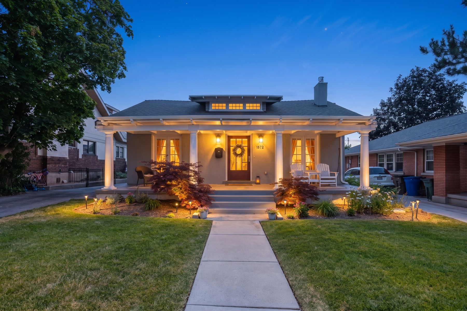 Craftsman-style facade featuring a covered porch with white columns, a dark wood entry door, and a transom window above