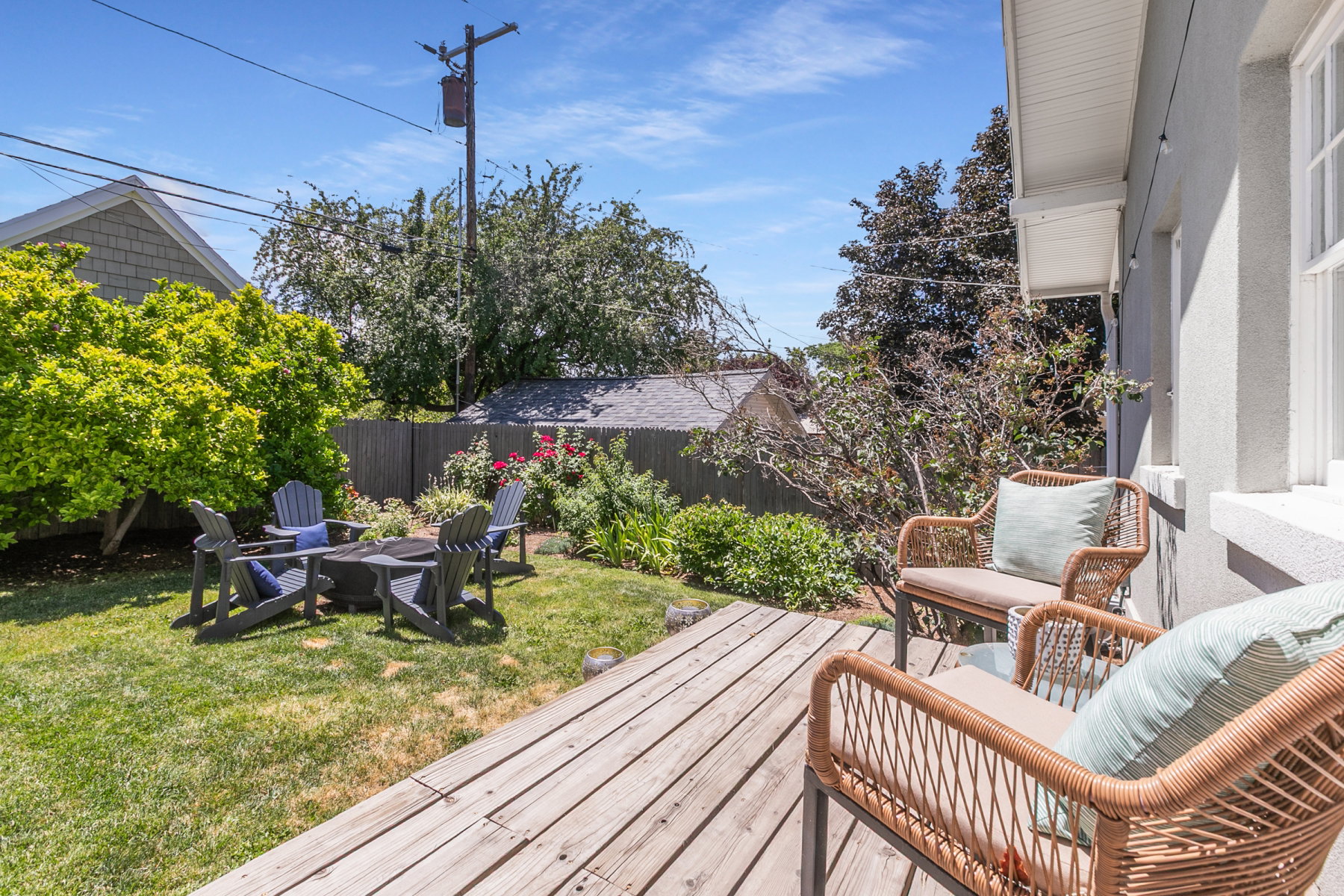 Outdoor living area featuring a wooden deck, a grassy yard, and mature landscaping