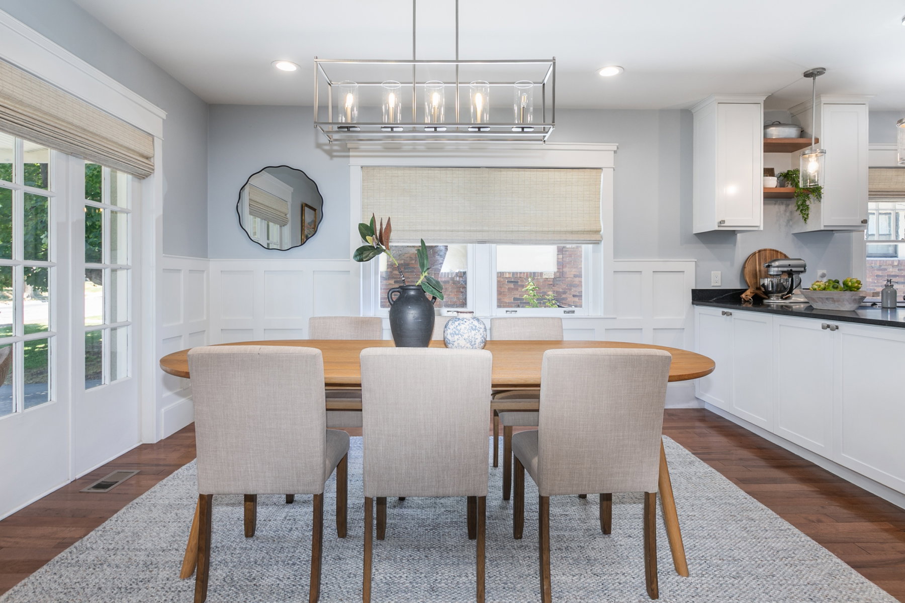 Dining area featuring wood-finish flooring, wainscoting, and a linear chandelier