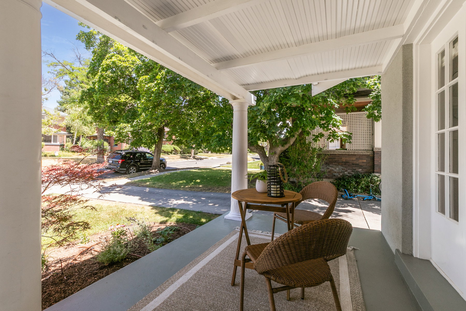 Covered front porch with classic columns, beadboard ceiling, and a paneled entry door with glass inserts