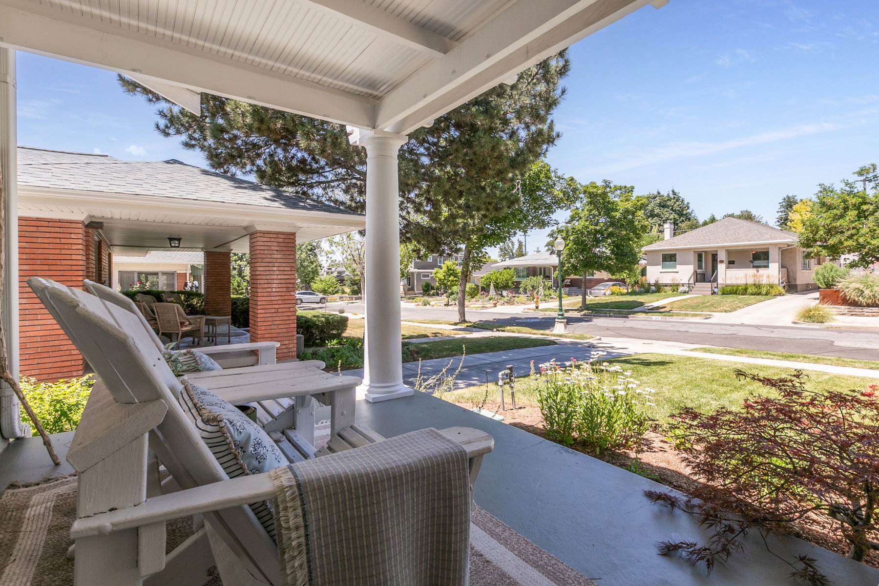 Covered front porch featuring white columns and a beadboard ceiling