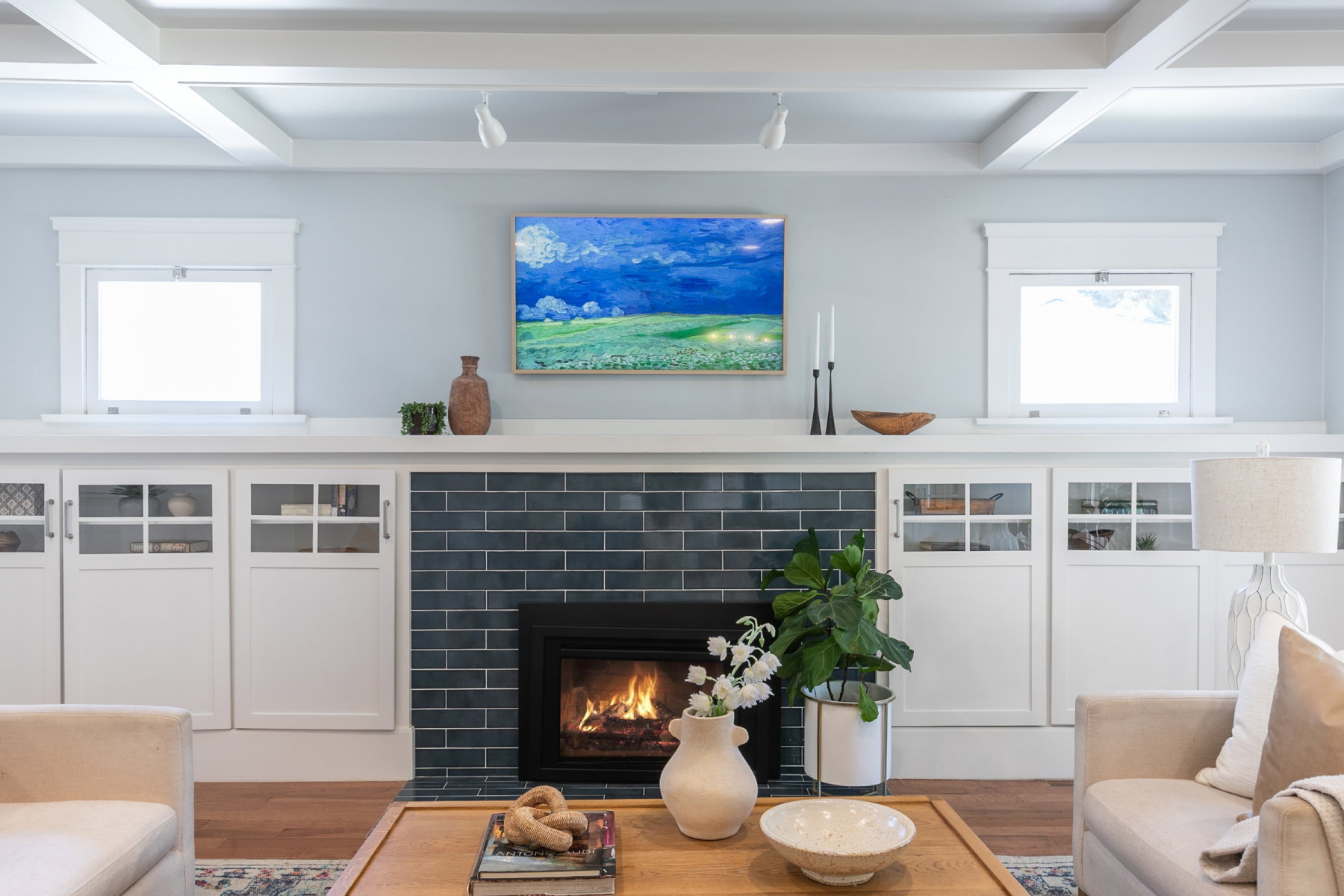 Built-in cabinetry with glass-front doors frames a fireplace featuring dark subway tile and a black firebox