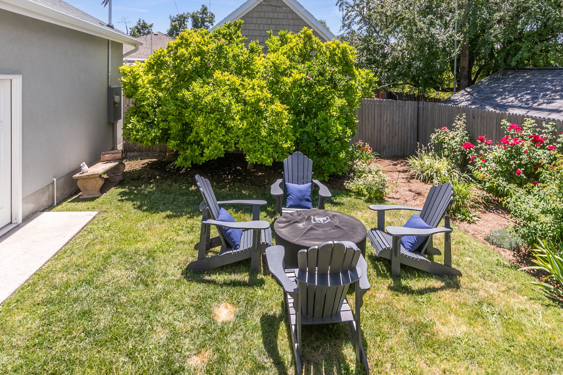 Expansive backyard featuring a manicured lawn, established shrubbery, a concrete walkway, and a privacy fence