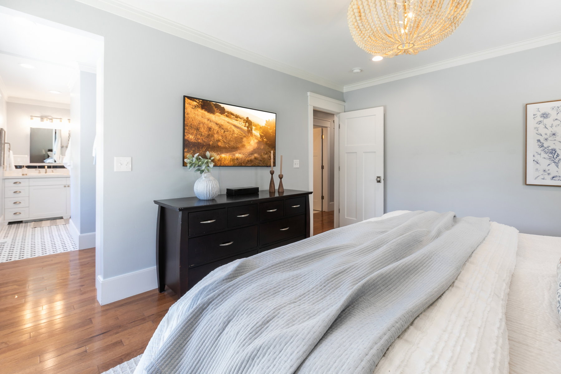 Spacious room featuring hardwood flooring, light blue wall paint, and white crown molding