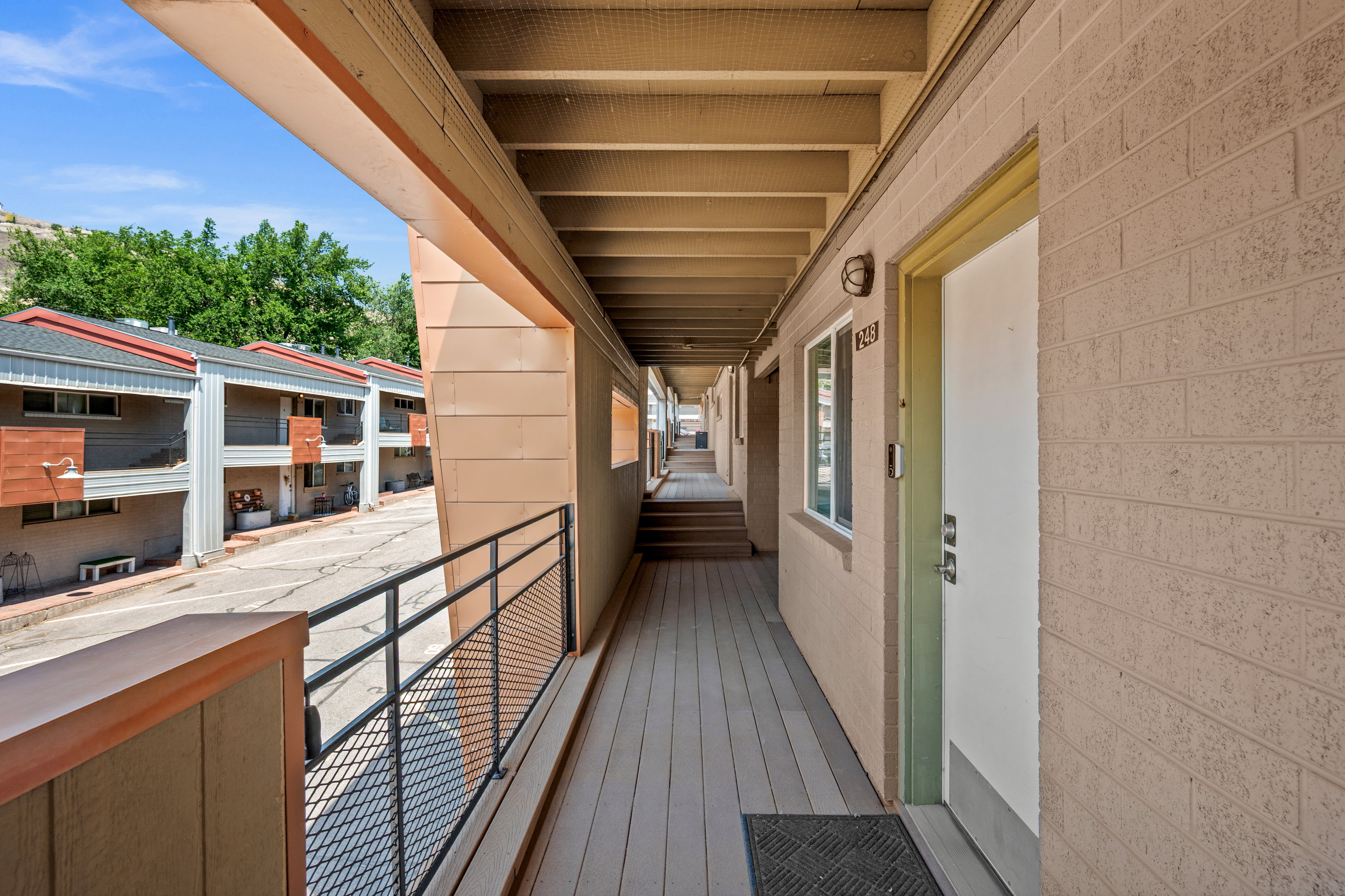 Covered exterior walkway featuring composite decking and a black metal railing