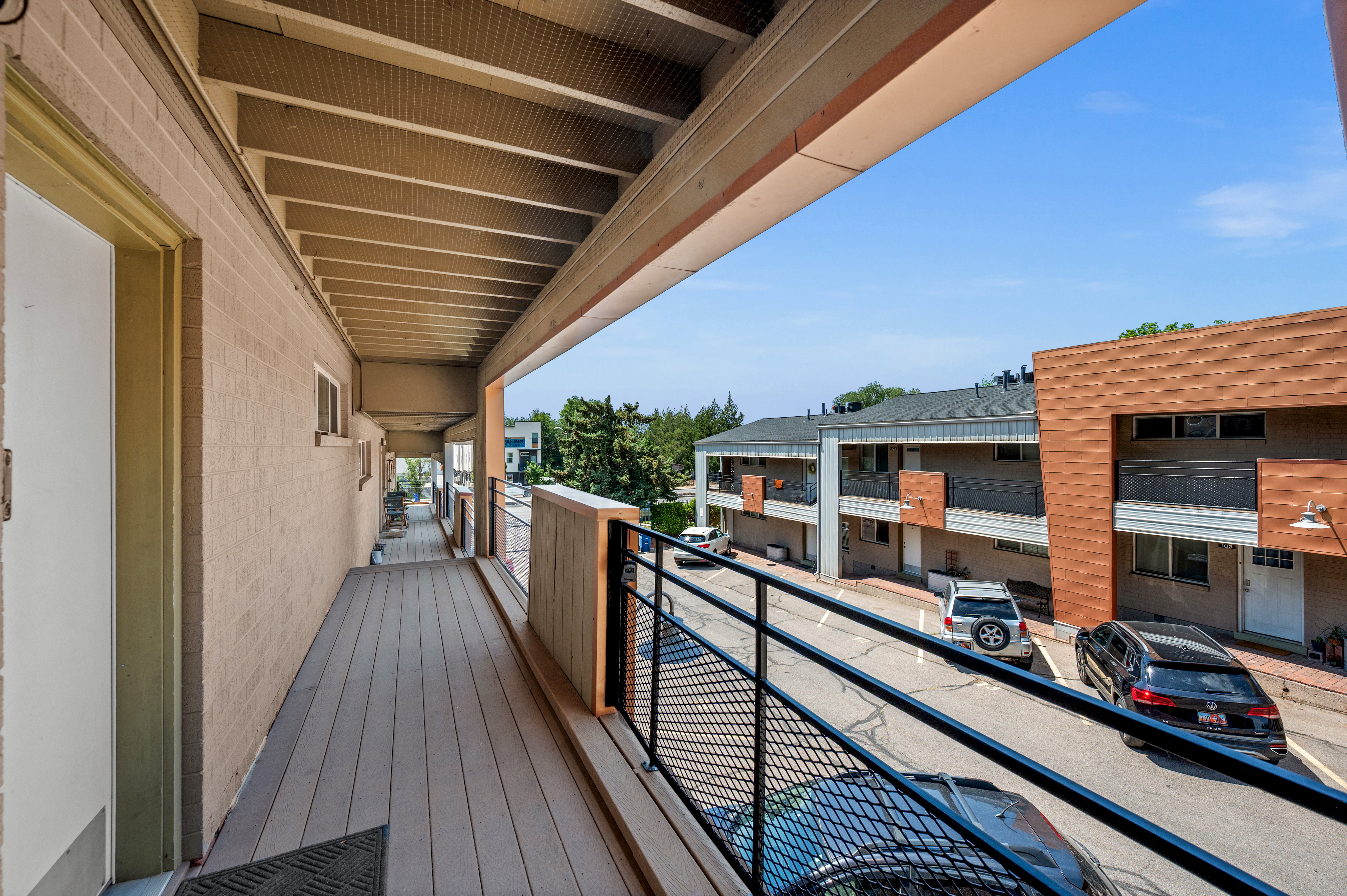 Covered outdoor balcony featuring composite decking and a black metal railing