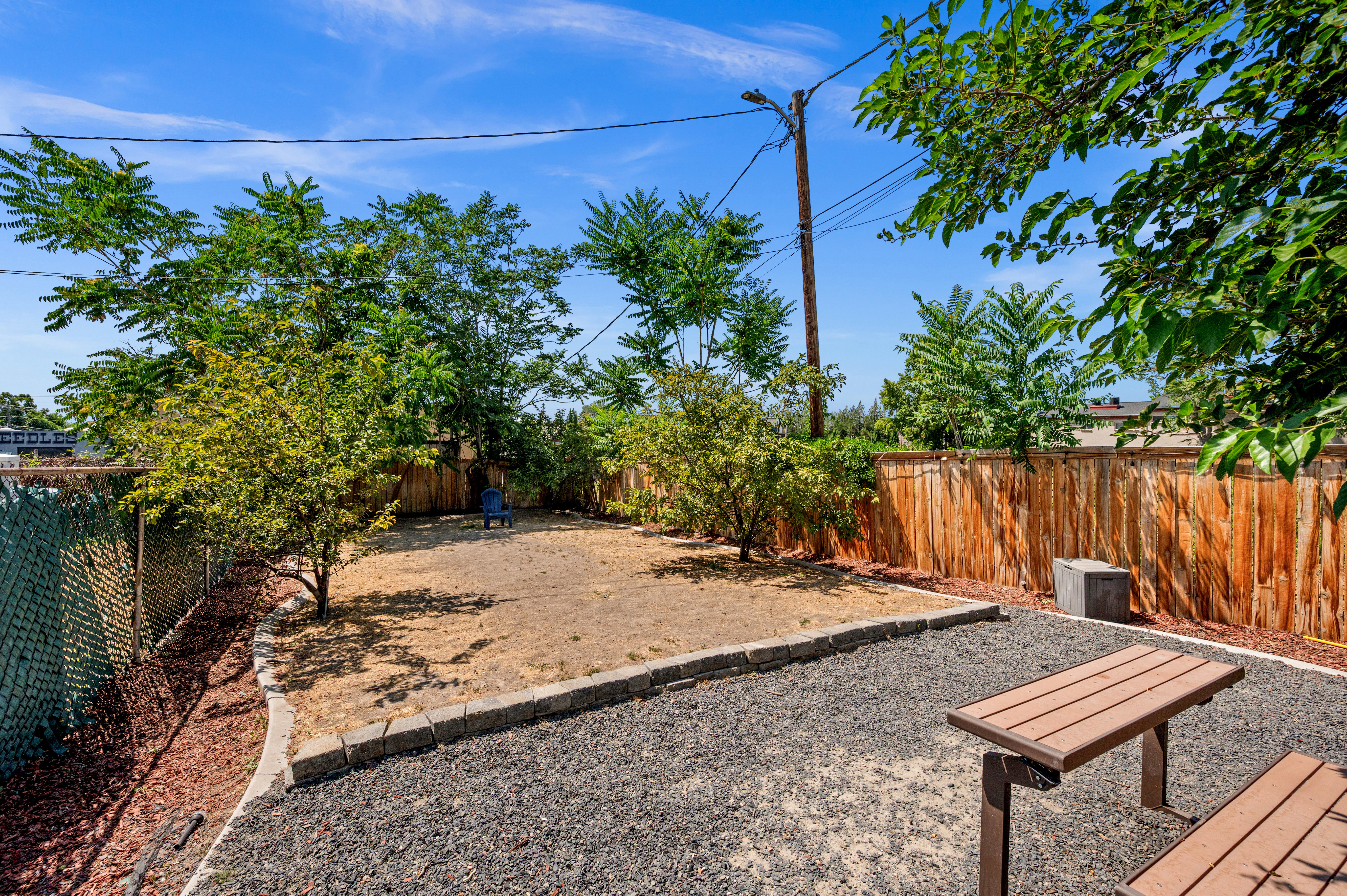 Spacious outdoor area with a wood-slat fence and mature trees