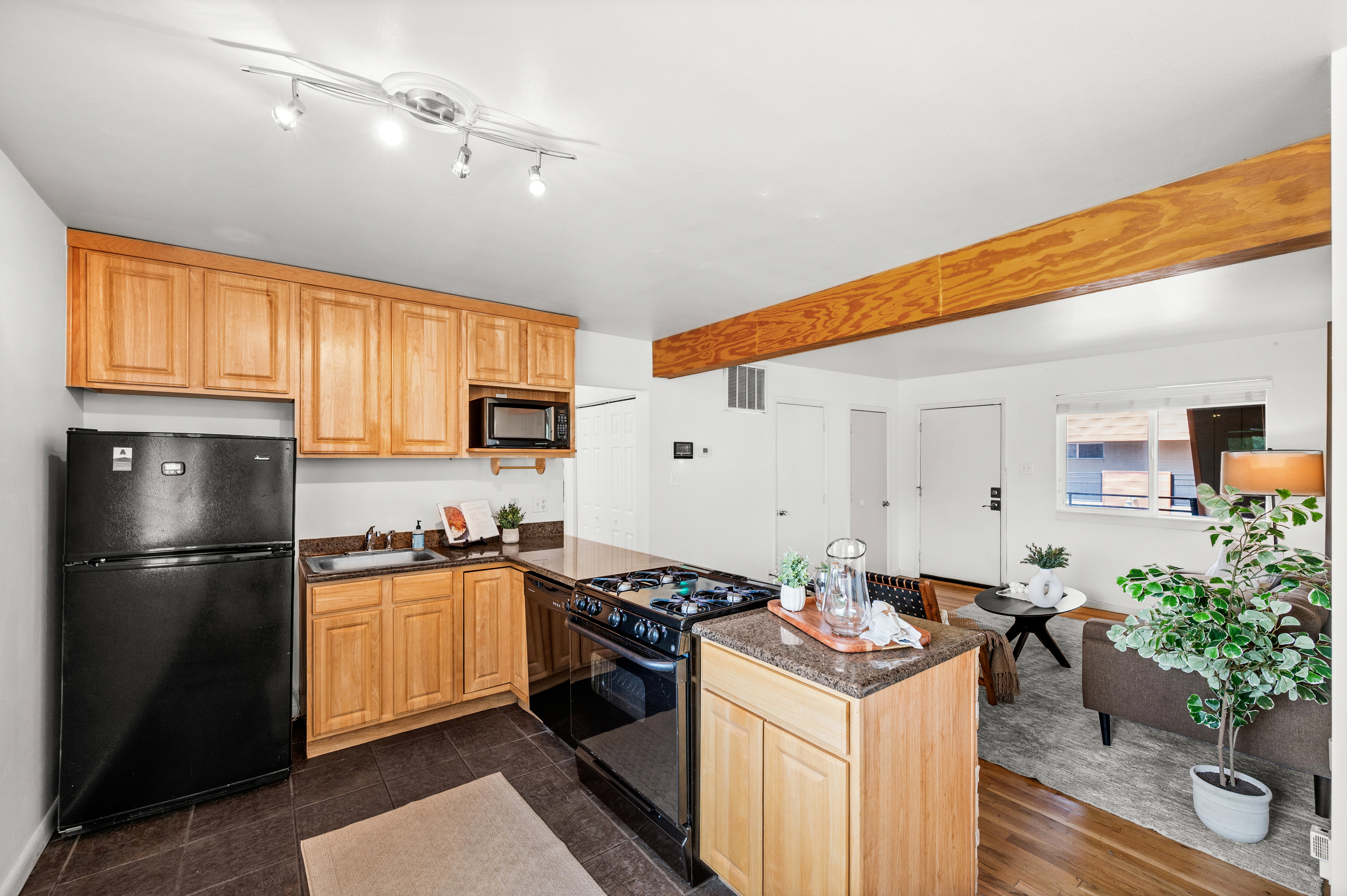Kitchen featuring natural wood-finish cabinetry, dark countertops, and track lighting