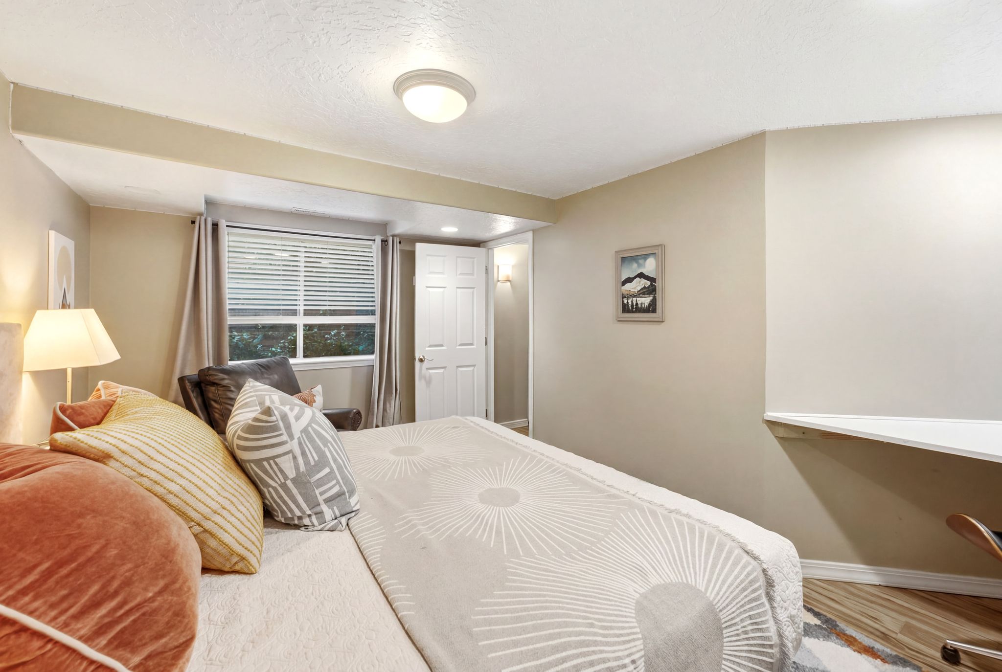 Bedroom featuring neutral wall colors, a window with horizontal blinds, wood-finish flooring, a white paneled door, and a built-in corner desk