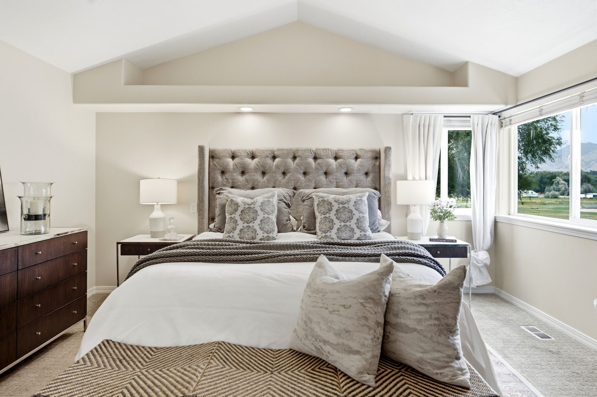 Vaulted ceiling with recessed lighting and neutral-toned walls