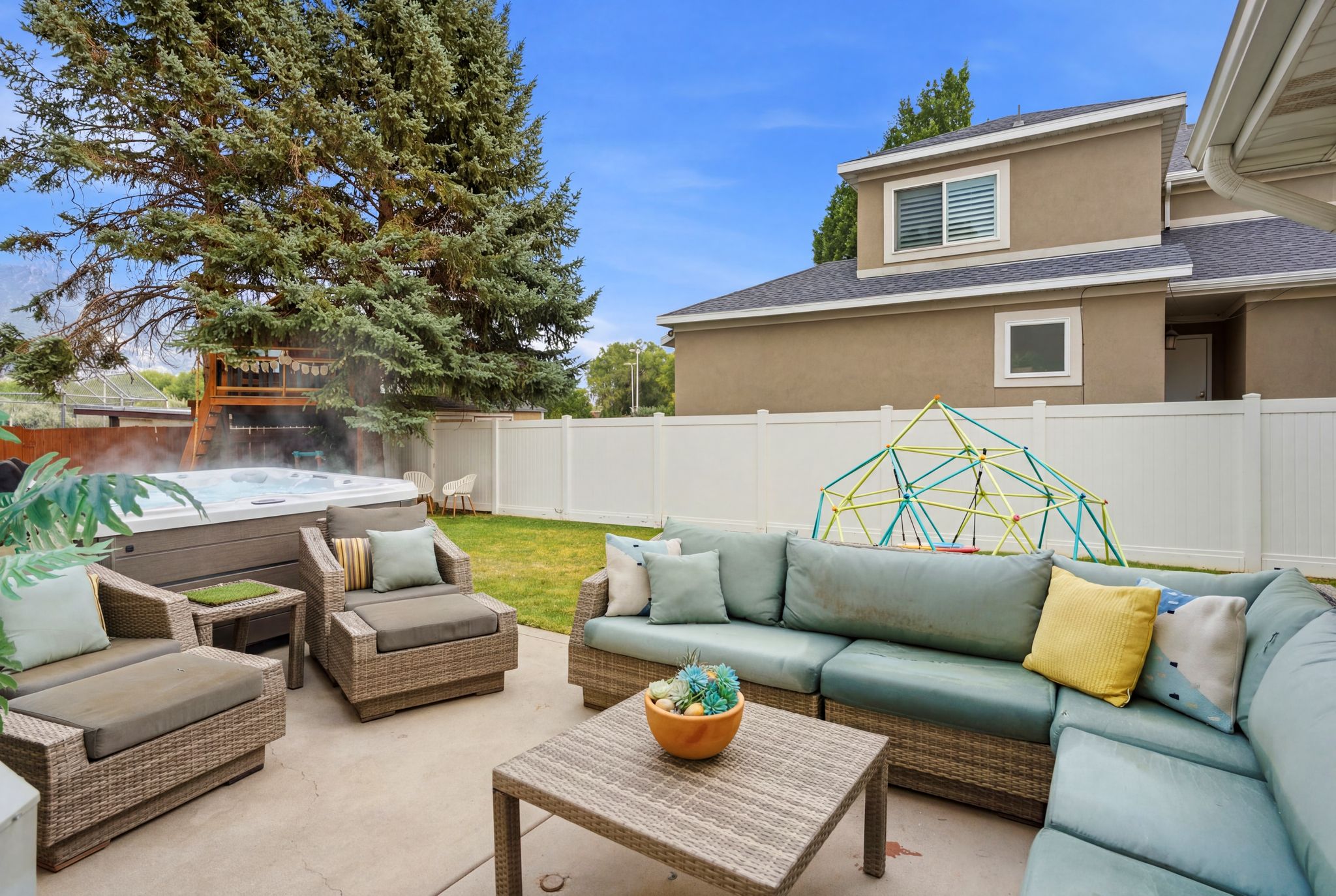 Expansive backyard featuring a concrete patio, a built-in hot tub, and a privacy fence